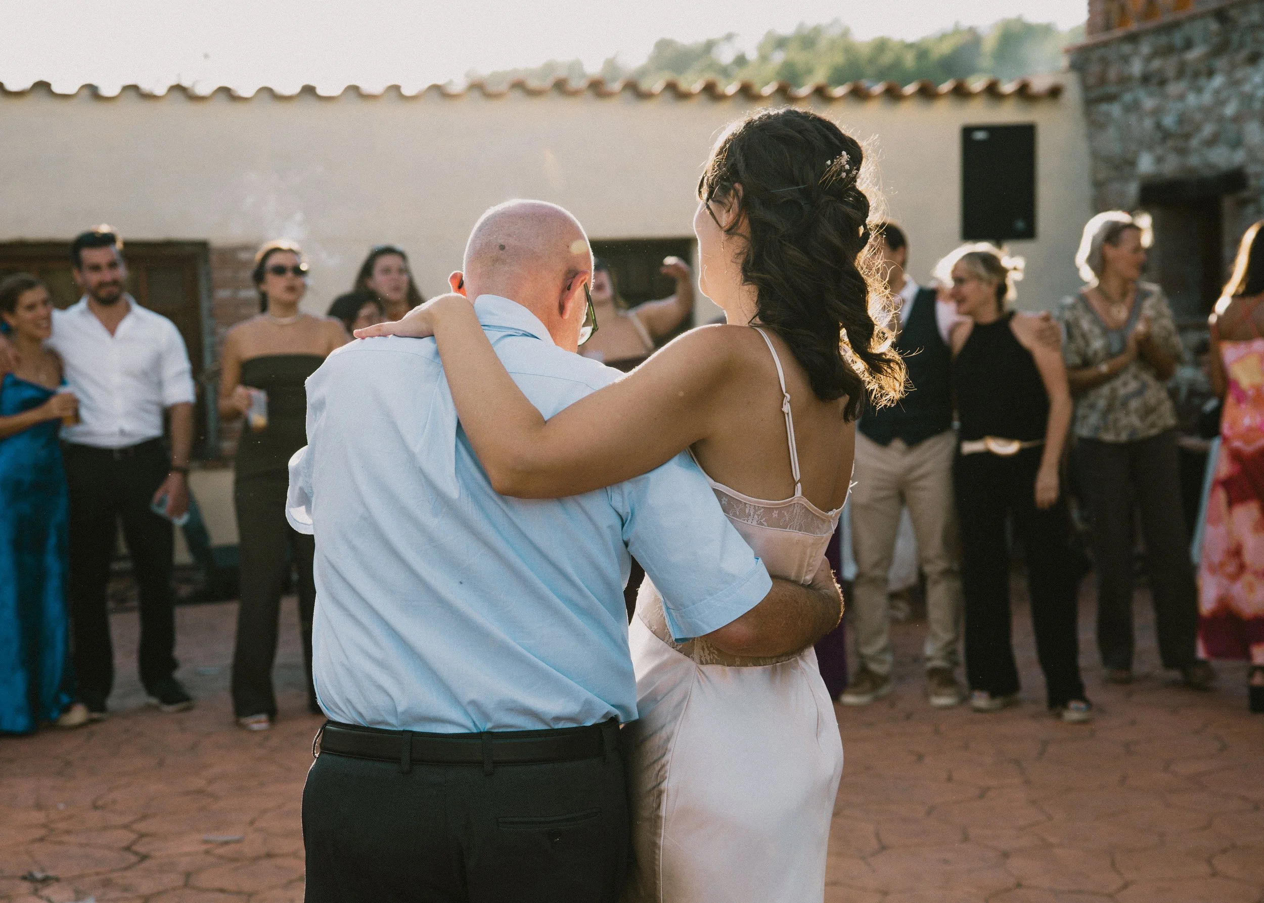 Pareja bailando en una boda al aire libre con invitados observando y aplaudiendo.