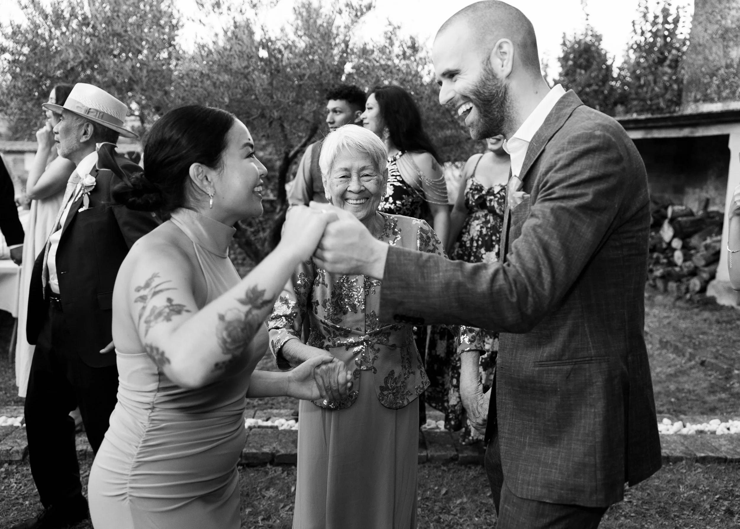 Personas bailando en una ceremonia al aire libre, incluyendo un hombre con barba y mujer con tatuajes y vestido ajustado.