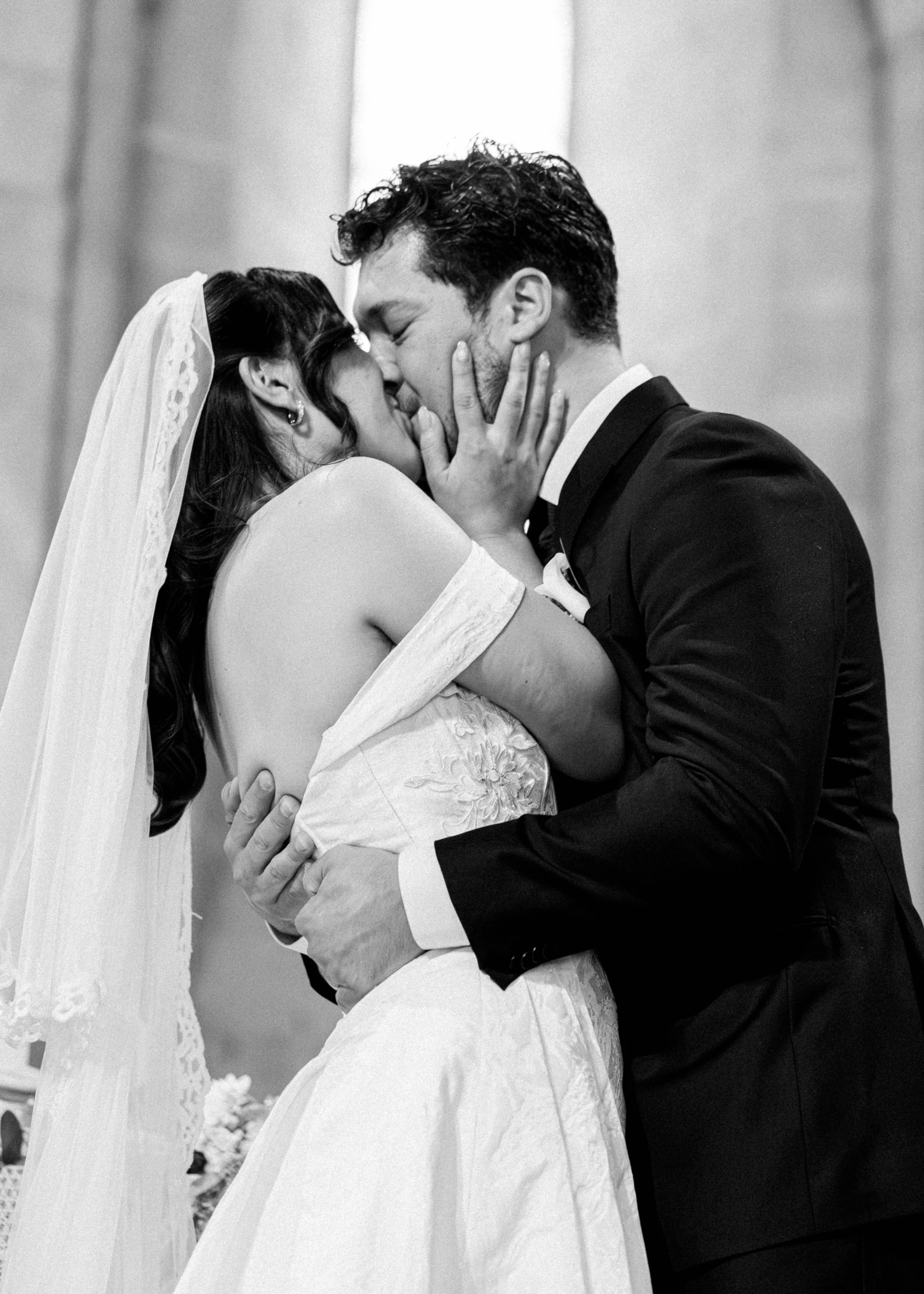 Pareja de novios besándose en una boda, en negro y blanco.