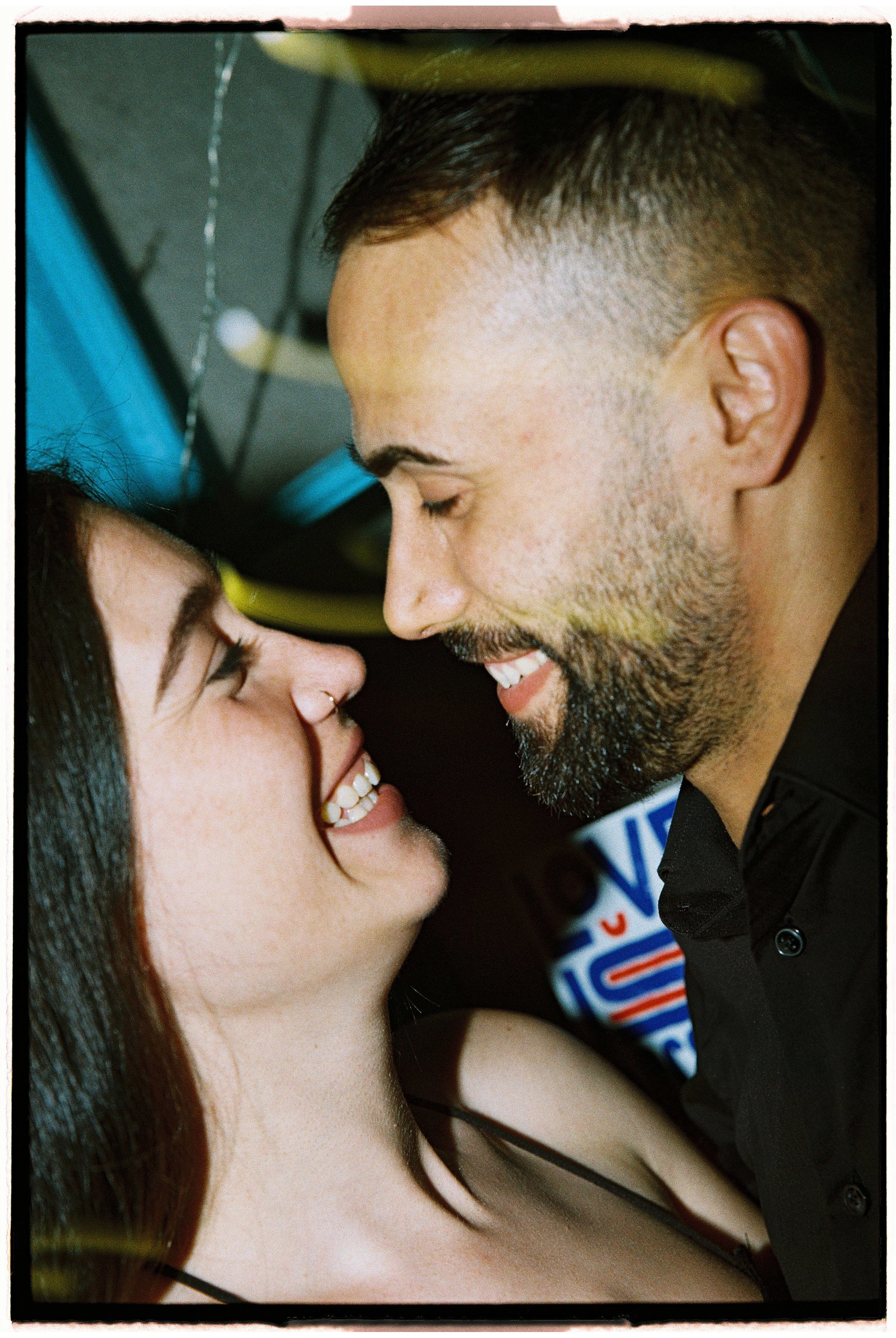 Una pareja sonriendo con los rostros muy juntos, en un momento íntimo y feliz.