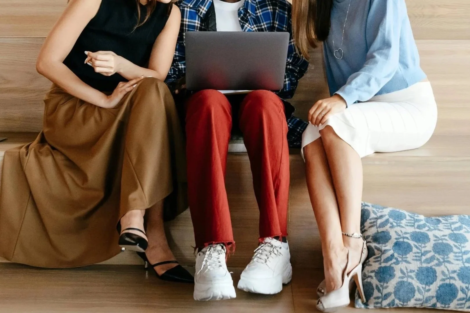 A group of 3 individuals sit around a computer representing inclusive nature of couples therapy to include alternative relationship structures