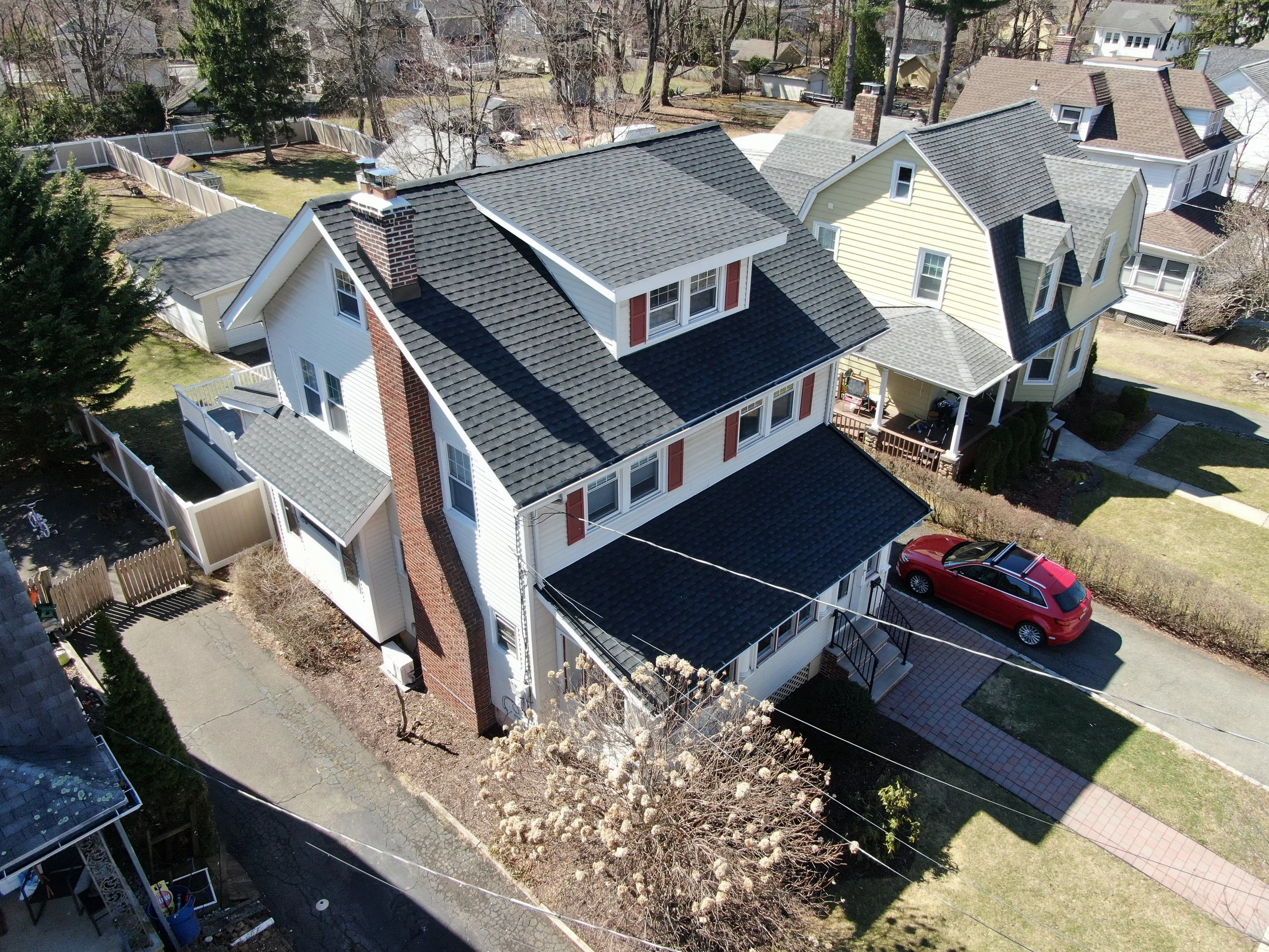 Aerial view of completed roof replacement in Caldwell, NJ with UHDZ Charcoal shingles and new chimney flashing (completed).