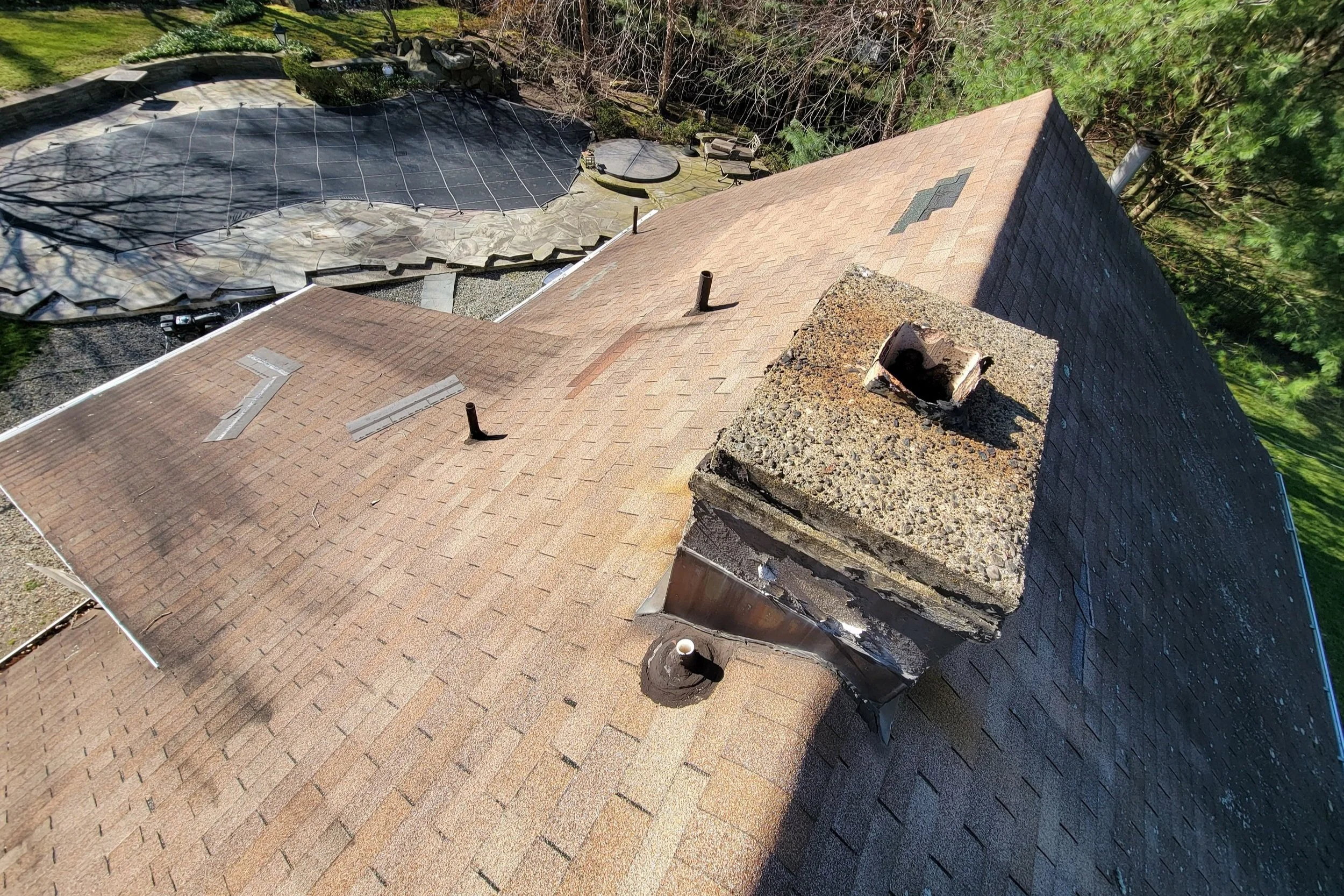 Caldwell, NJ roof inspection photo showing missing 3-tab shingles and tarred pipe collars around roof penetrations.