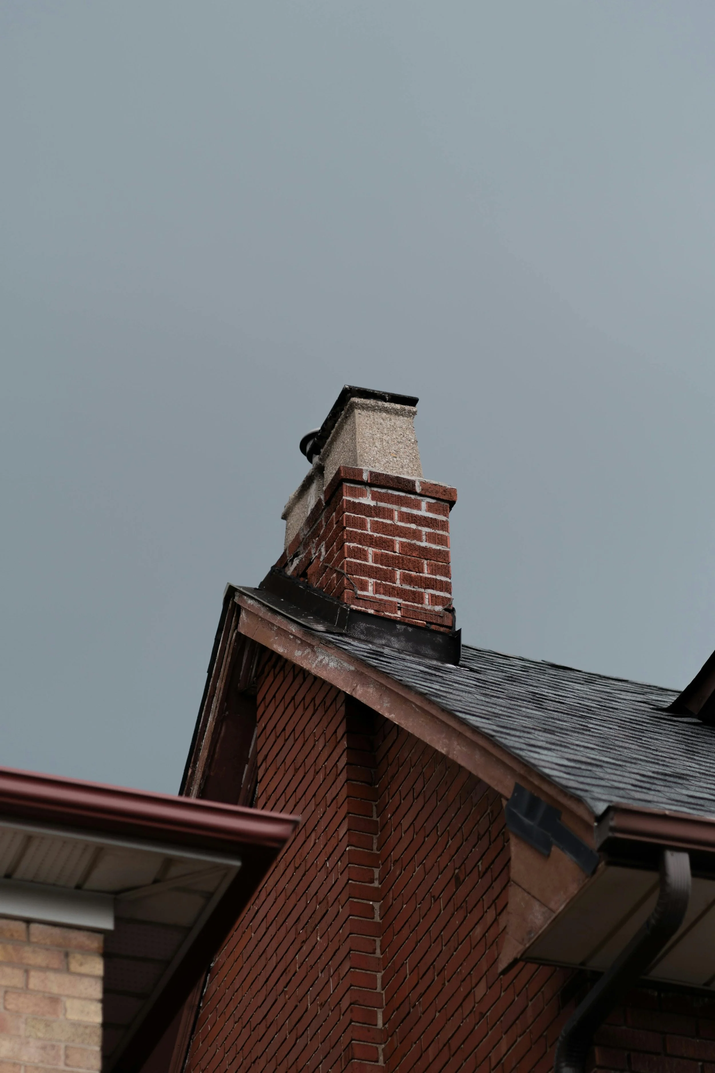 Low level picture of a brick chimney with partially failing flashing.