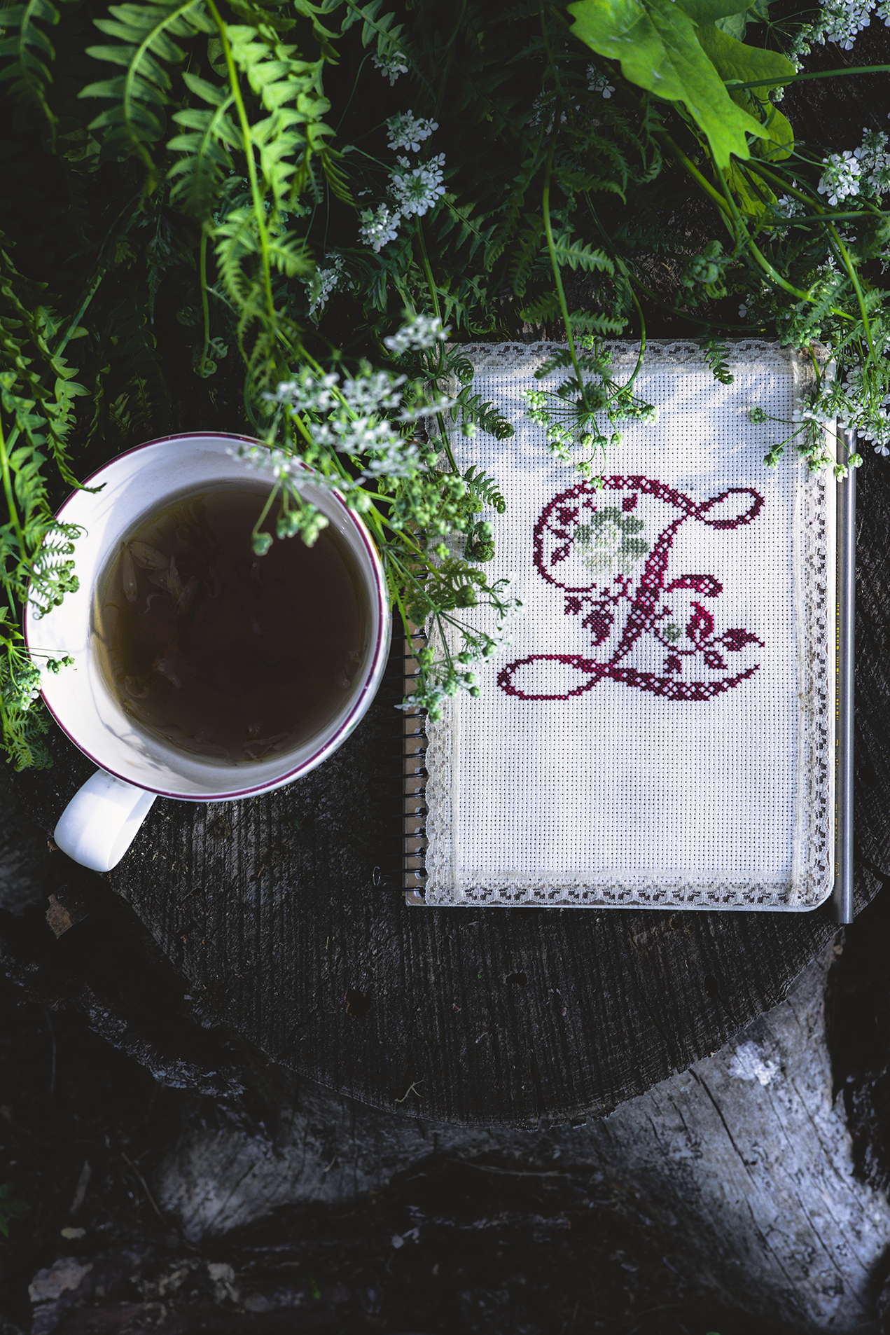 Tea and an embroidered journal among green ferns