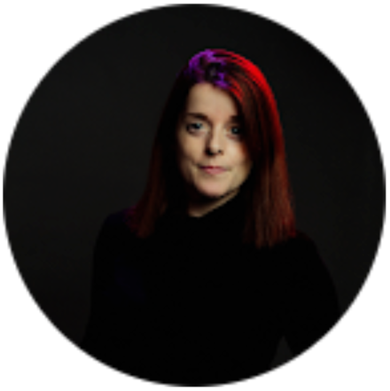 Portrait d’une femme aux cheveux mi-longs, partiellement roux et partiellement foncés, sur fond noir