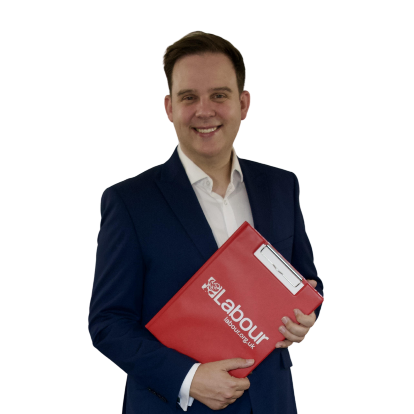 A smiling man wearing a suit, white shirt, and blue tie, holding a red folder that has the Labour party logo and website, standing against a plain gray background.
