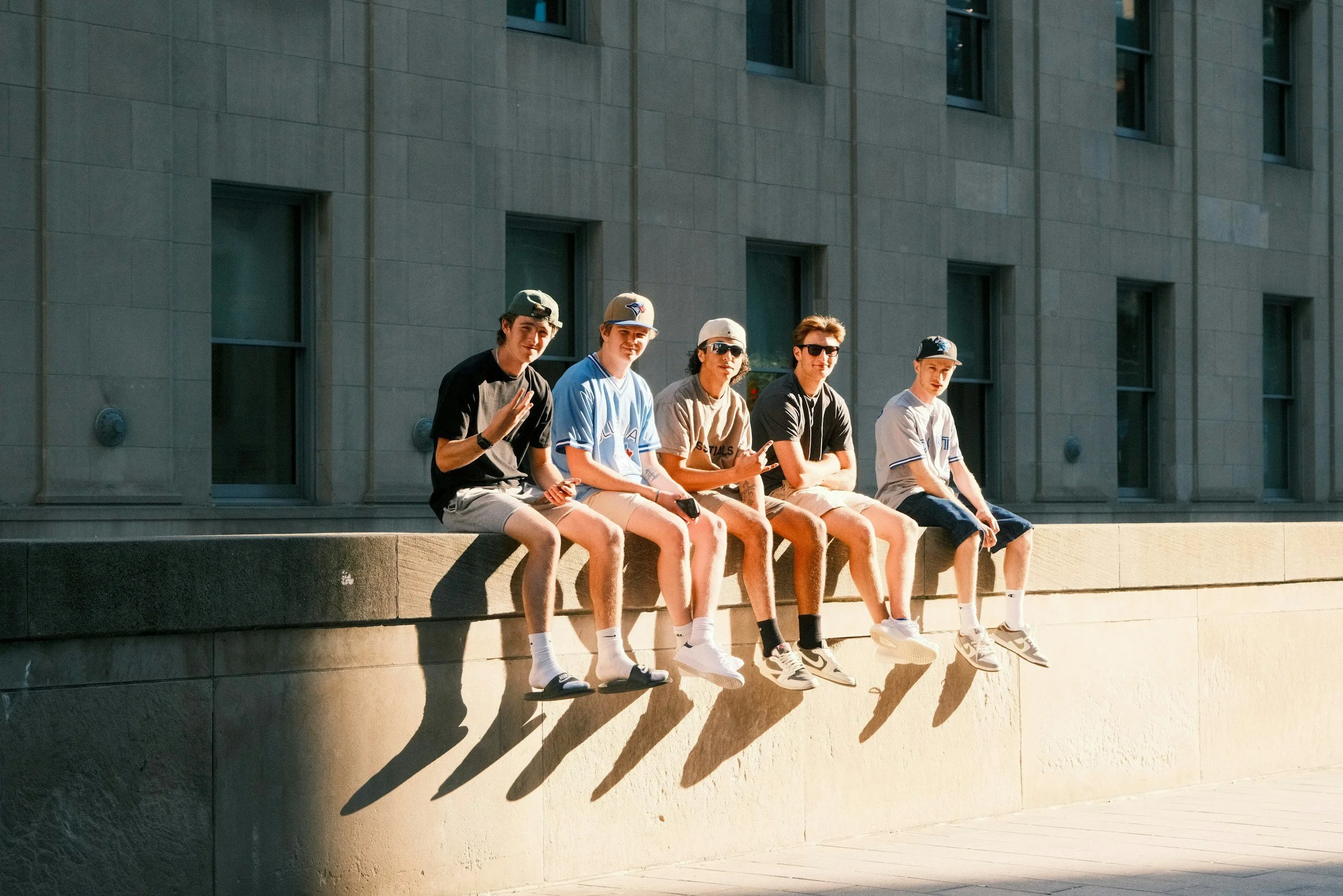 5 teenagers on a wall smiling at the camera