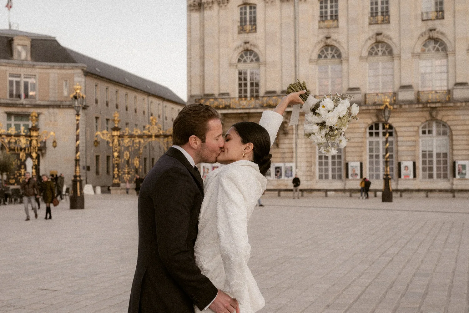 A bride and groom embrace on a Parisian square.