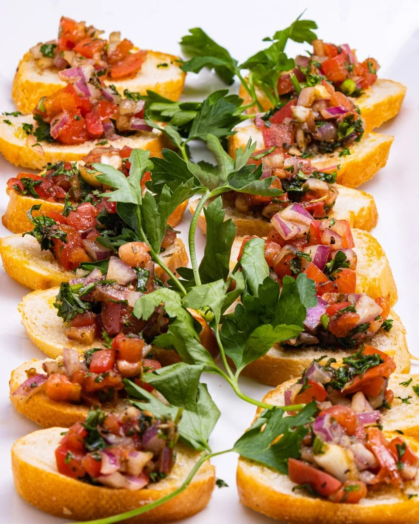 Close-up of Italian bruschetta with chopped tomatoes, onions, herbs, and garnished with fresh parsley on toasted baguette slices.