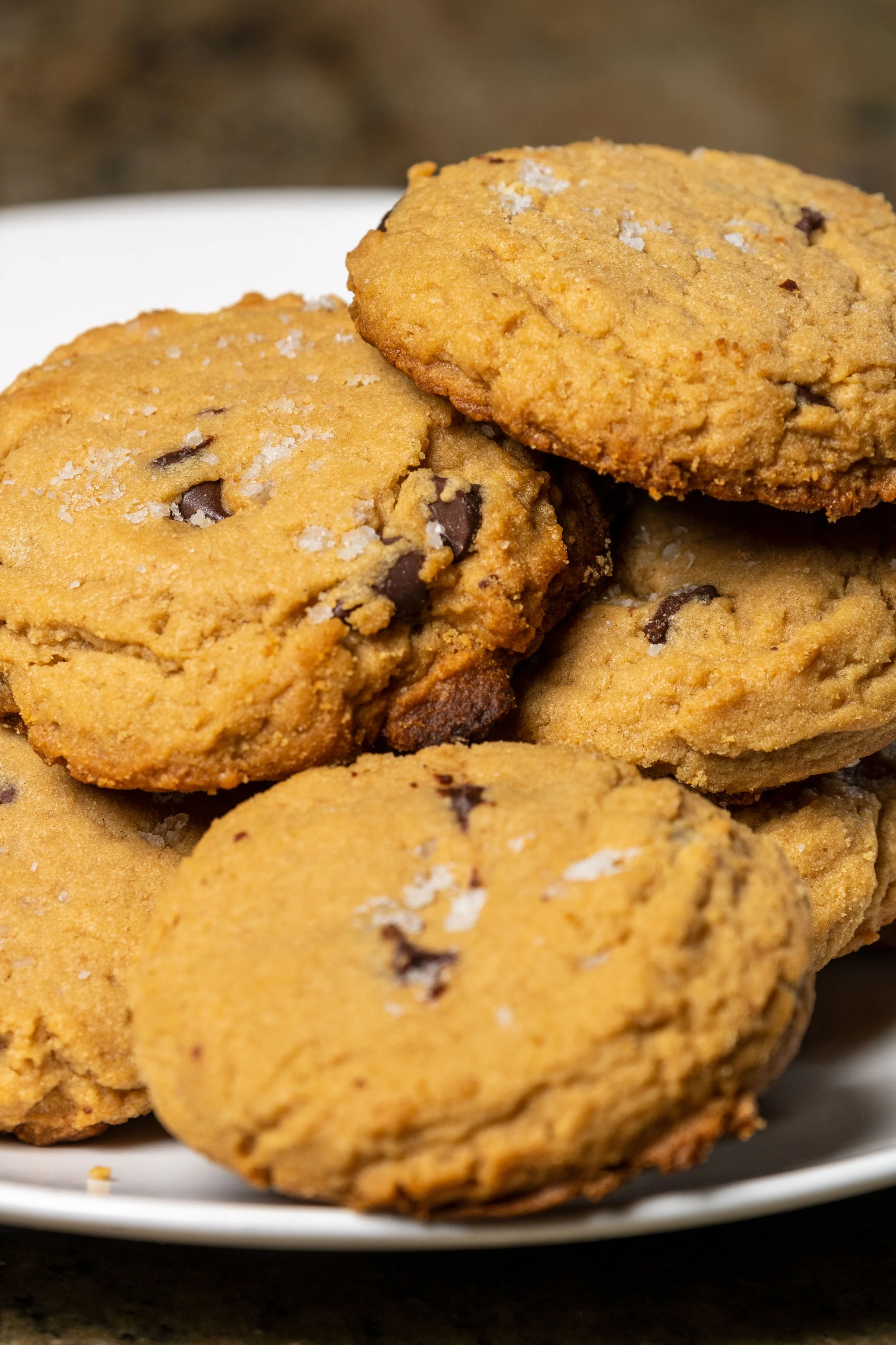 Close-up of a white plate filled with chocolate chip cookies sprinkled with sea salt.