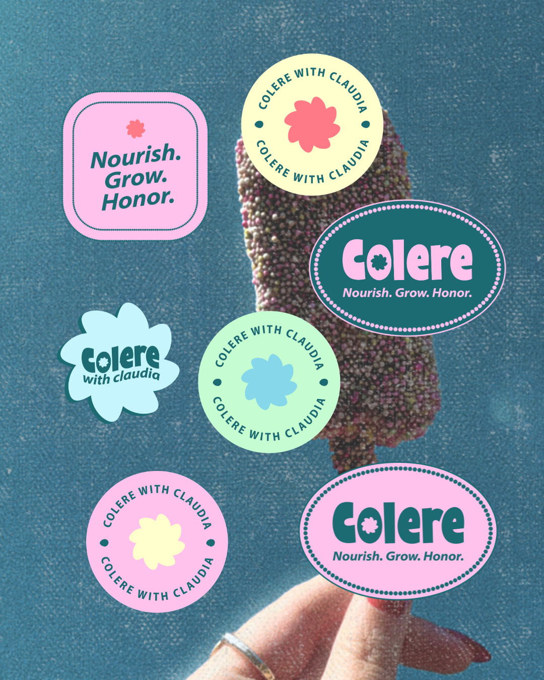 A hand holding a blackberry with multiple colorful stickers on it, including sayings like 'Nourish. Grow. Honor.' and 'Colere with Claudia' in various shapes and colors.