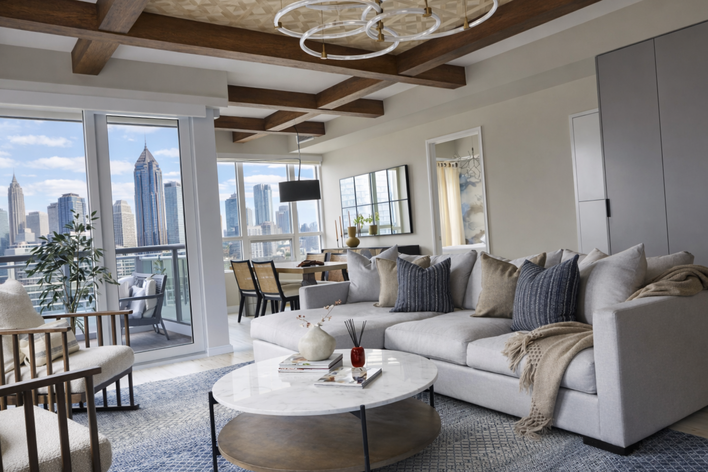 Luxury living room design in Atlanta with skyline views, a white sectional sofa, and a marble coffee table. Large windows and balcony access create an open, light-filled space that reflects modern interior design and high-end home styling.