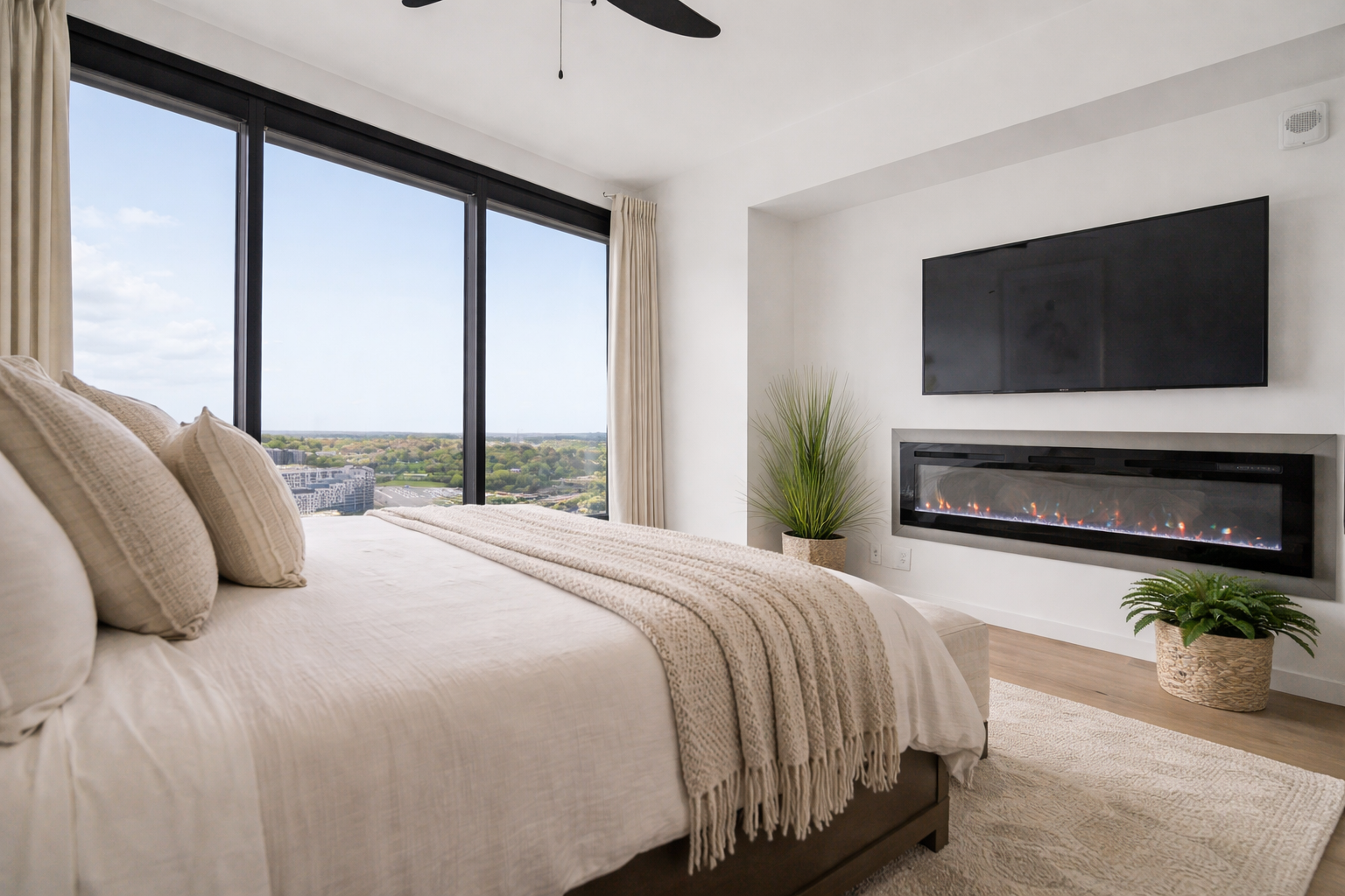 Contemporary bedroom with expansive windows, a modern fireplace, and neutral furnishings, designed for comfort and sophistication. This space highlights luxury interior styling and elevated living for modern Atlanta homes.
