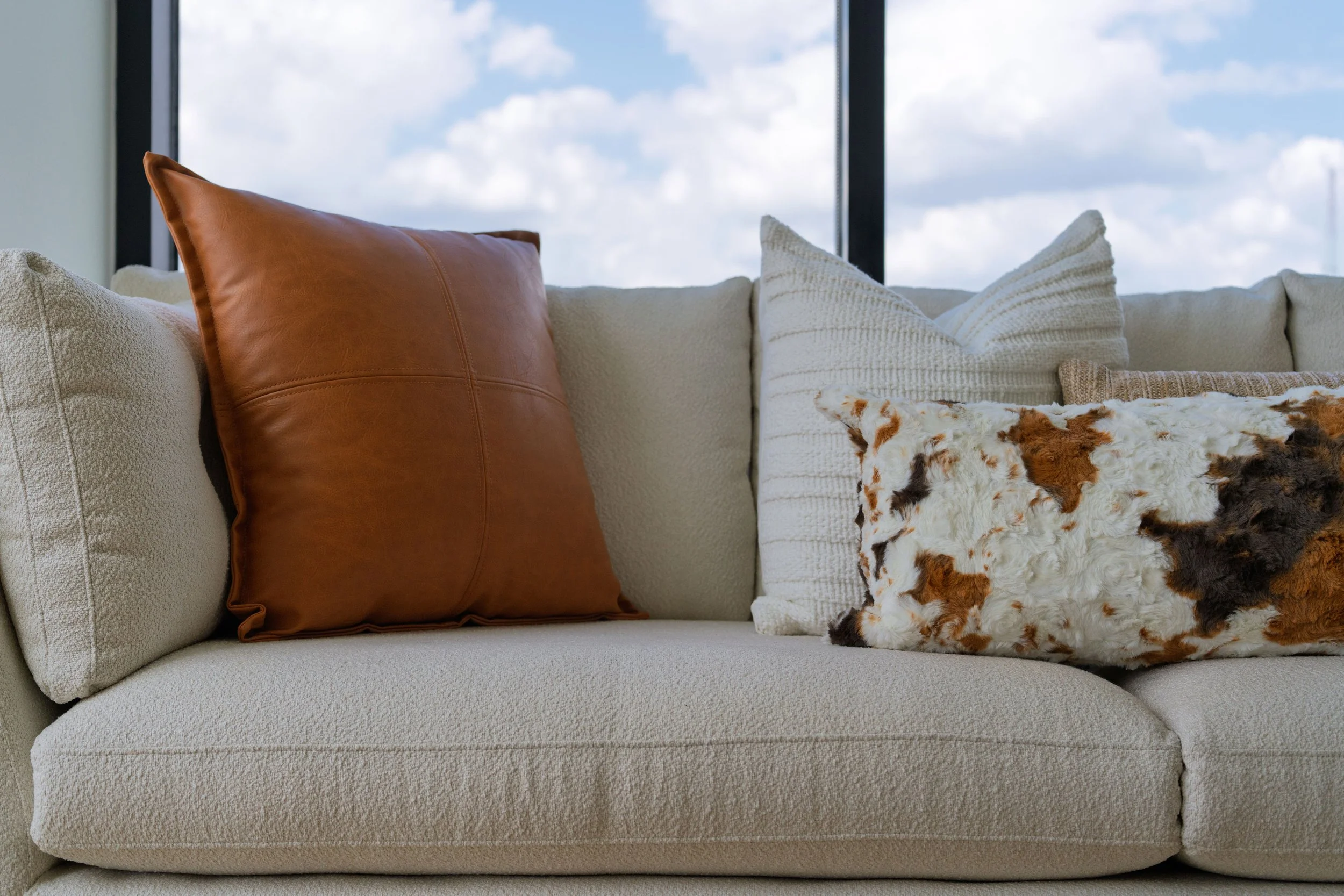 Detail of a styled sofa with layered decorative pillows and rich textures, showcasing intentional interior styling, curated accents, and luxury home decor details.