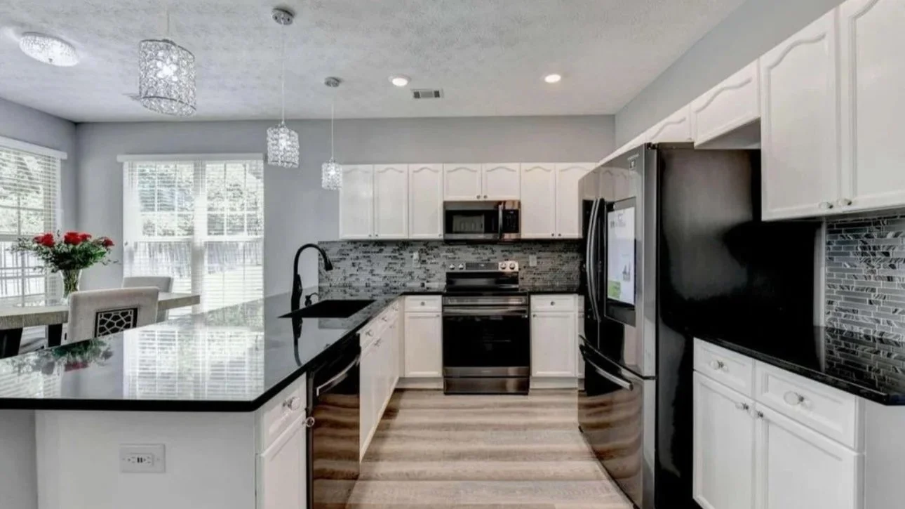 Modern luxury kitchen design featuring white cabinetry, black countertops, and styled dining space. This interior showcases professional home staging, interior styling, and elevated kitchen design for Atlanta homes.