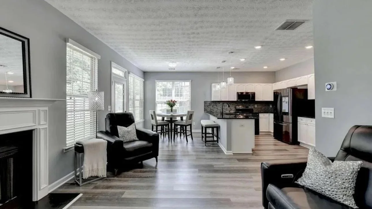 Transformed open-concept living room and kitchen featuring modern finishes, white cabinetry, black accents, and updated styling. This design showcases luxury interior styling, home staging, and cohesive space planning for Atlanta homes.
