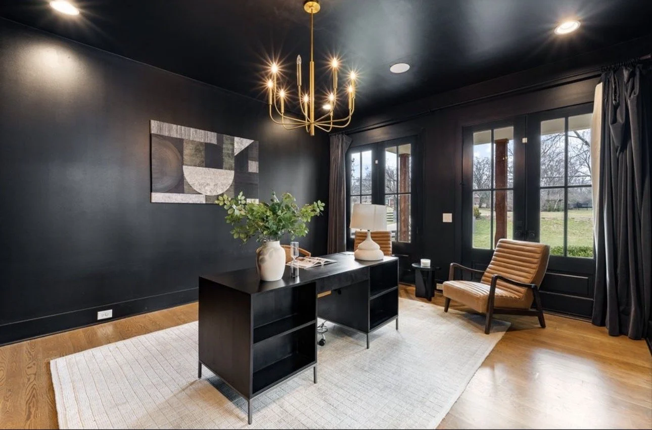 Contemporary home office design in Atlanta featuring black walls, a modern desk, and large windows with natural light. Styled with neutral textures and gold accents, this space reflects bold, upscale interior design and executive-level workspace styl