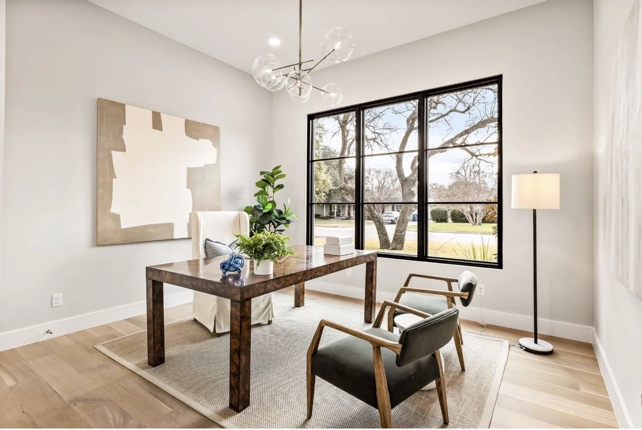 Modern home office design in Atlanta featuring a minimalist workspace with a wood desk, natural light, and large windows. This space reflects contemporary interior design with clean lines, functional layout, and a calm, productivity-focused environme