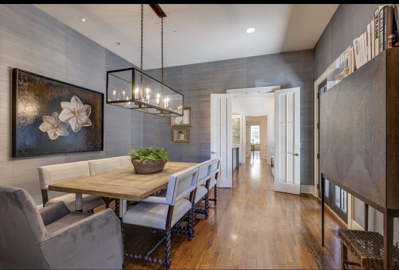 Elegant dining room design in Atlanta featuring a wood dining table, upholstered chairs, and a statement chandelier. Styled with greenery and wall art, this space reflects modern interior design with a warm, inviting, and high-end atmosphere.