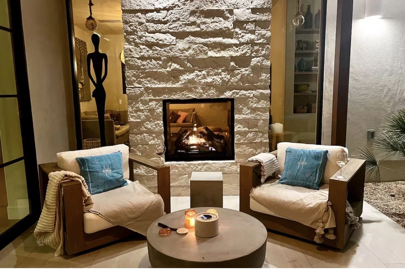 Cozy living room design in Atlanta featuring a fireplace, white armchairs with accent pillows, and soft ambient lighting. Styled with candles and decor, this space creates a warm, inviting atmosphere with a focus on comfort and luxury interior design