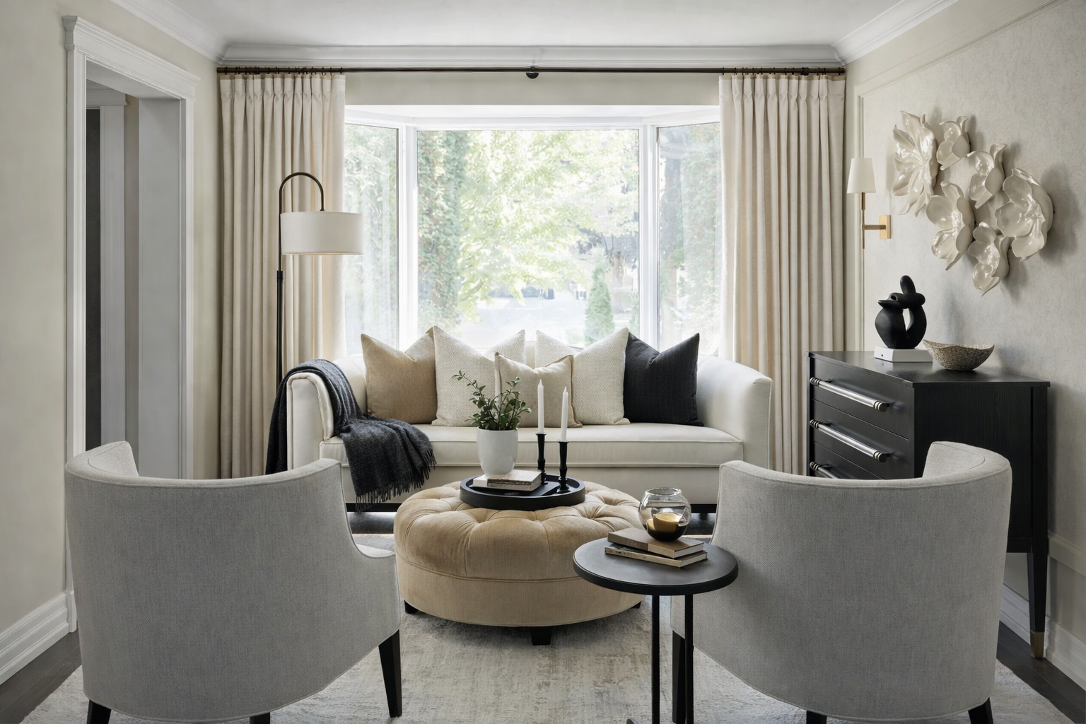 Elegant living room design in Atlanta with a white sofa, neutral-toned pillows, armchairs, and a styled ottoman. Featuring curated decor, natural light, and greenery, this space showcases luxury interior design with a warm, inviting atmosphere.