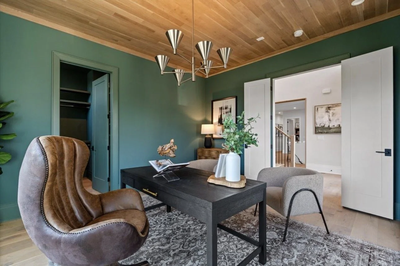 Modern home office design in Atlanta featuring a green accent wall, wood ceiling detail, and a styled desk with curated decor. This space blends natural textures, contemporary interior design, and functional workspace styling for a sophisticated, hig
