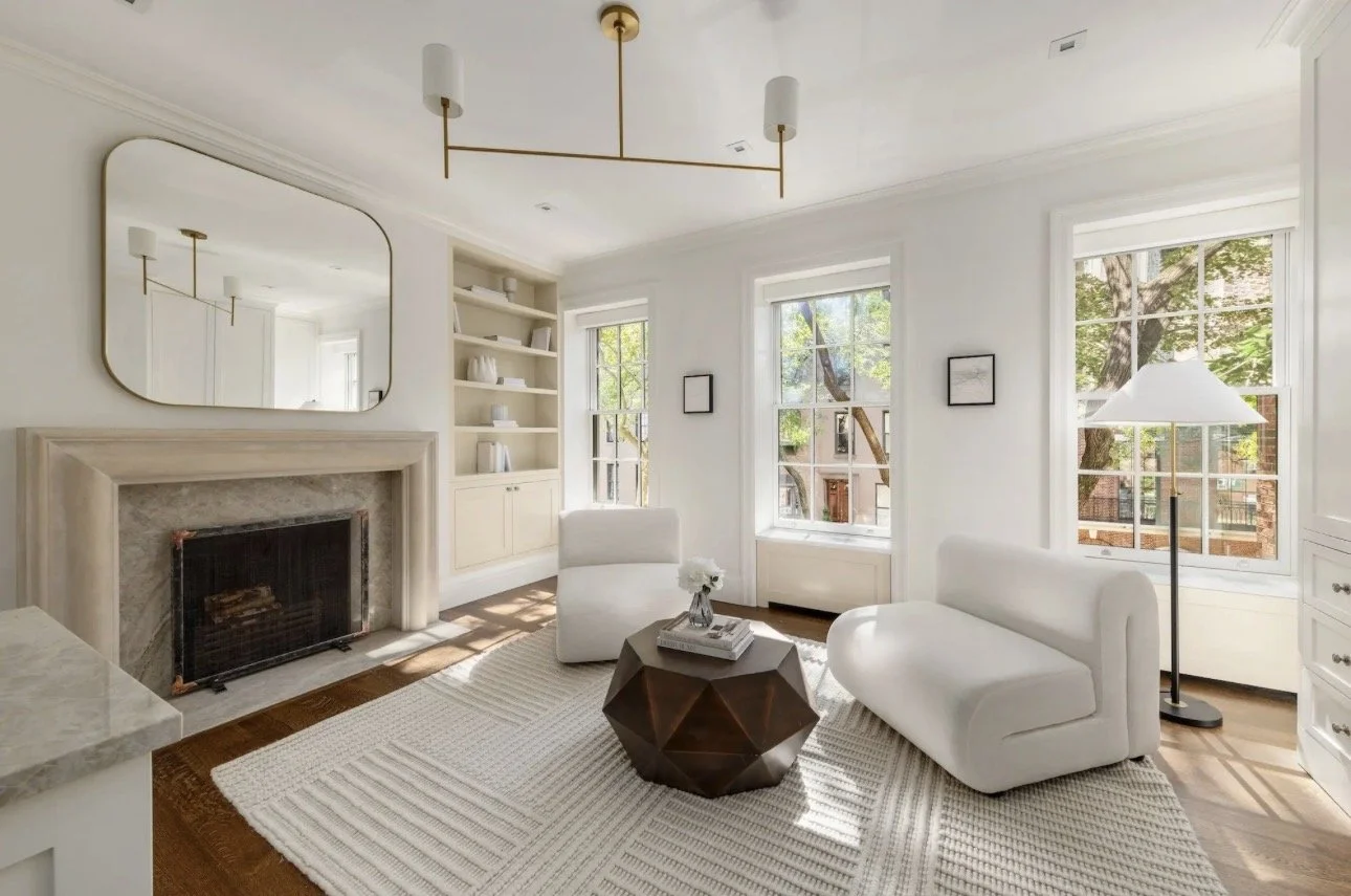 Luxury living room design in Atlanta featuring white walls, large windows, and a modern fireplace. Styled with dual white sofas, a geometric coffee table, and curated decor, this bright and airy space reflects contemporary interior design and upscale