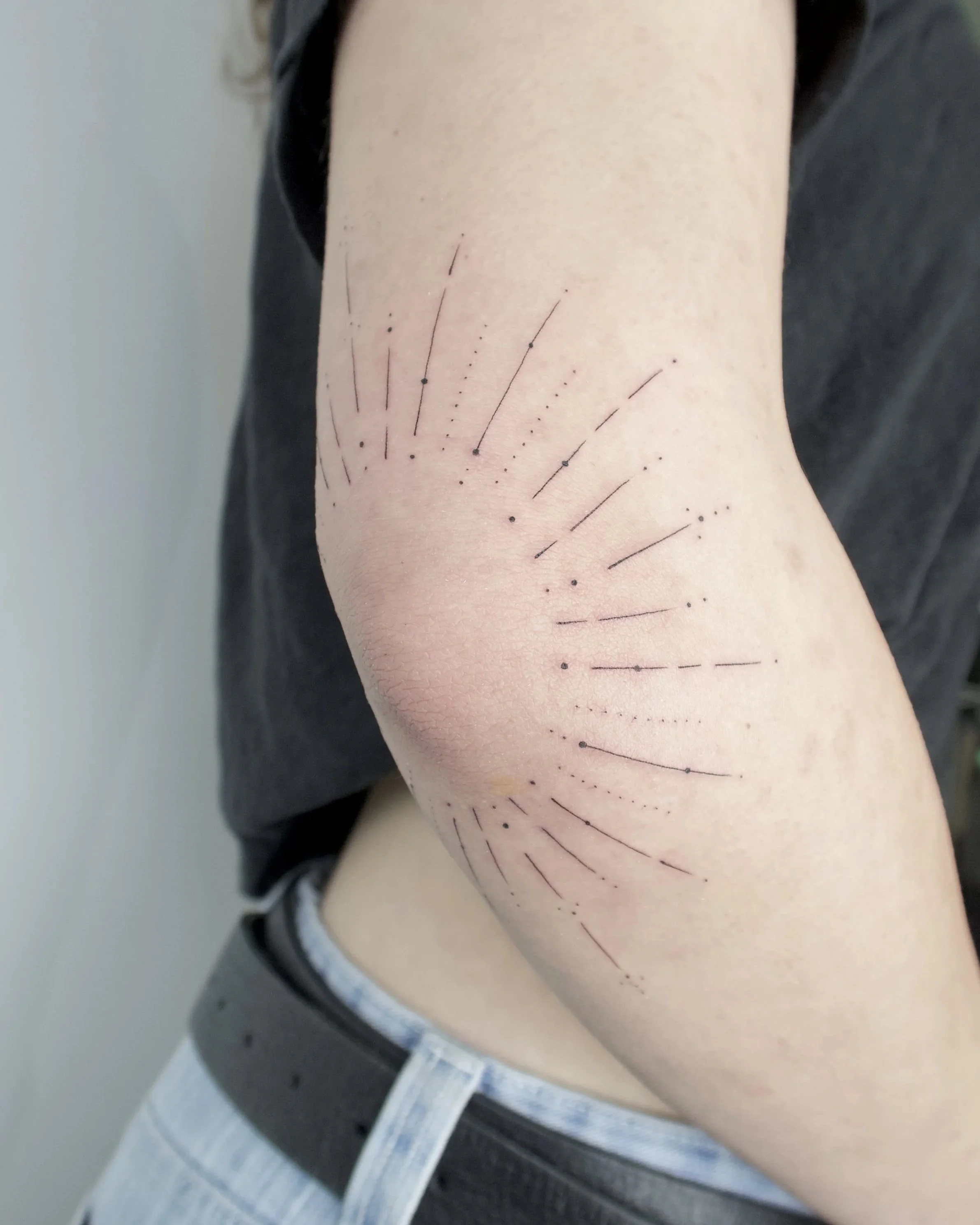zonnetje rondom elleboog lijnen fineline tattoo