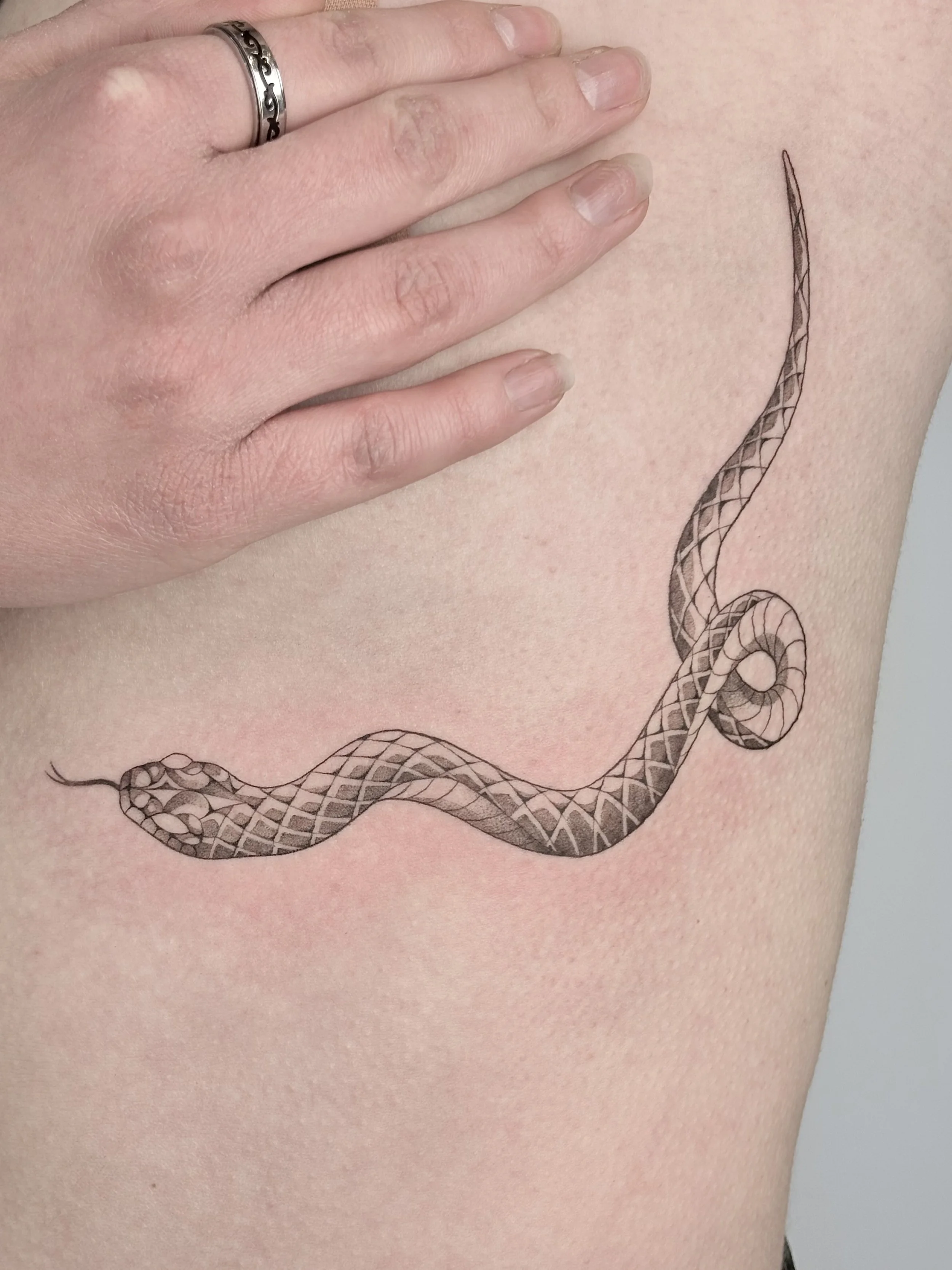 slangen tattoo fineline op rib rondom borst vrouw
