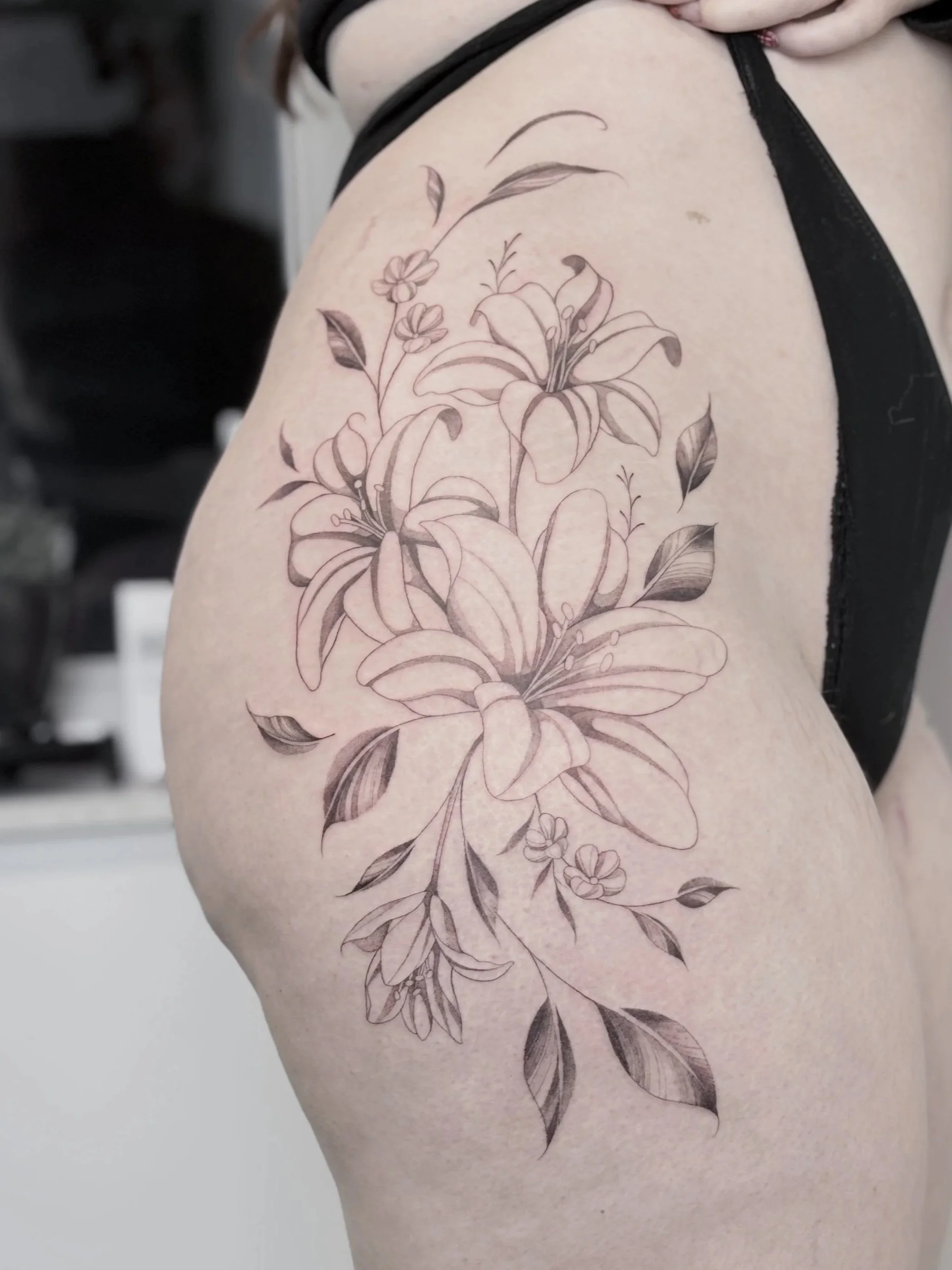 fineline lelies heup tattoo grote bloemen