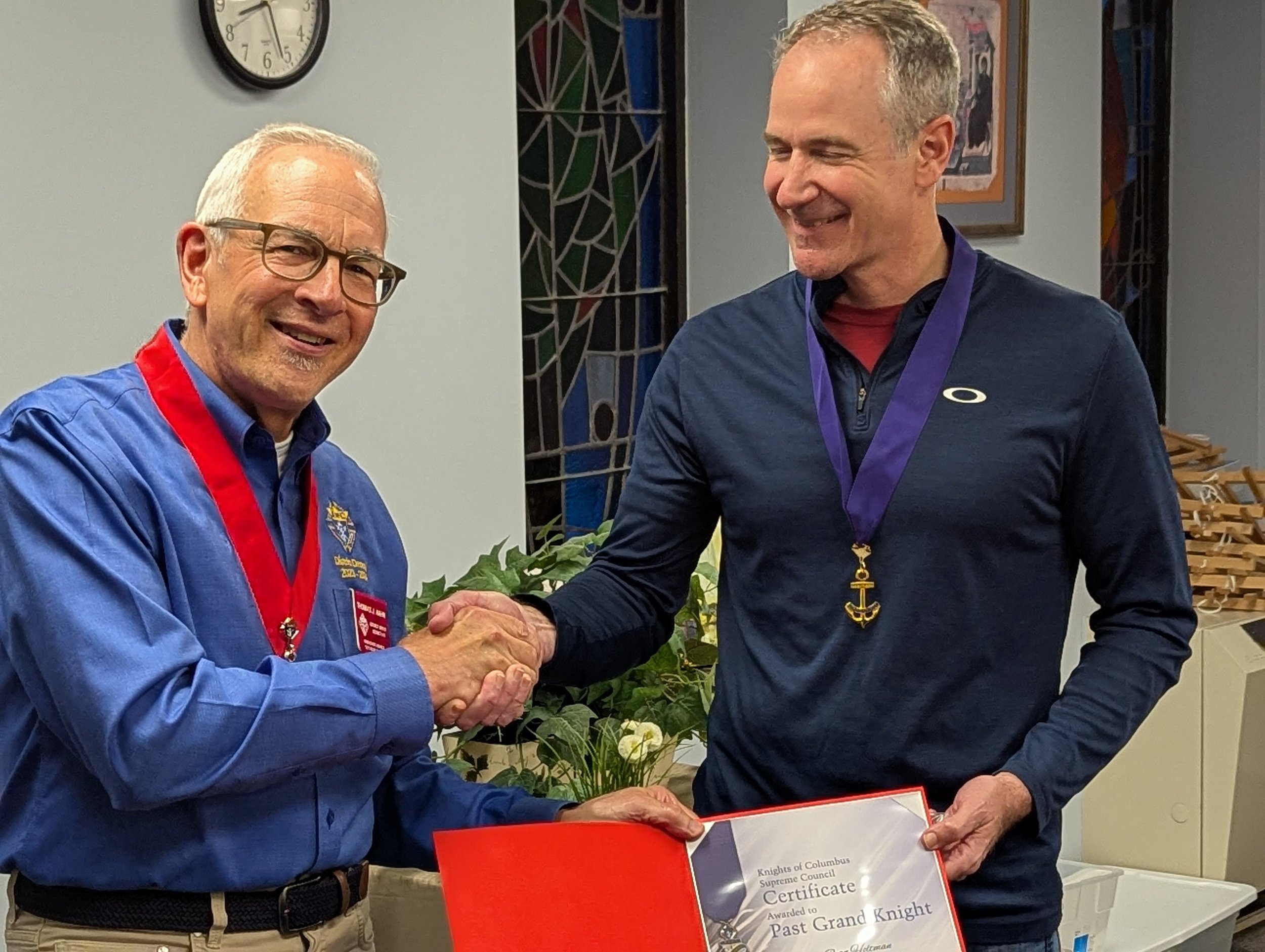 District Deputy Tom Hahn presents Grand Knight Ryan Holtman his certificate of recognition and pin upon completion of his term as Grand Knight.