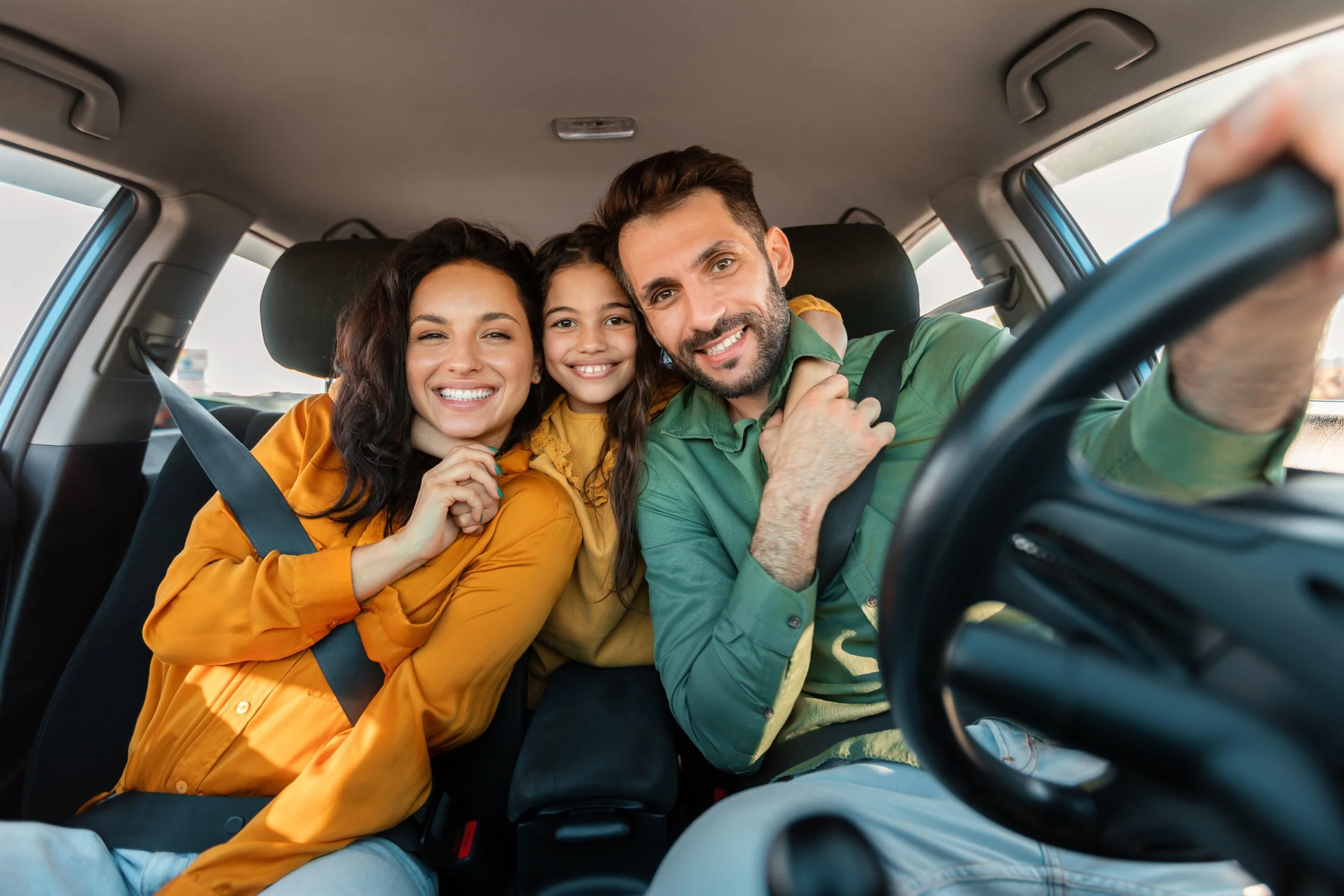 mum,dad and child in car smiling
