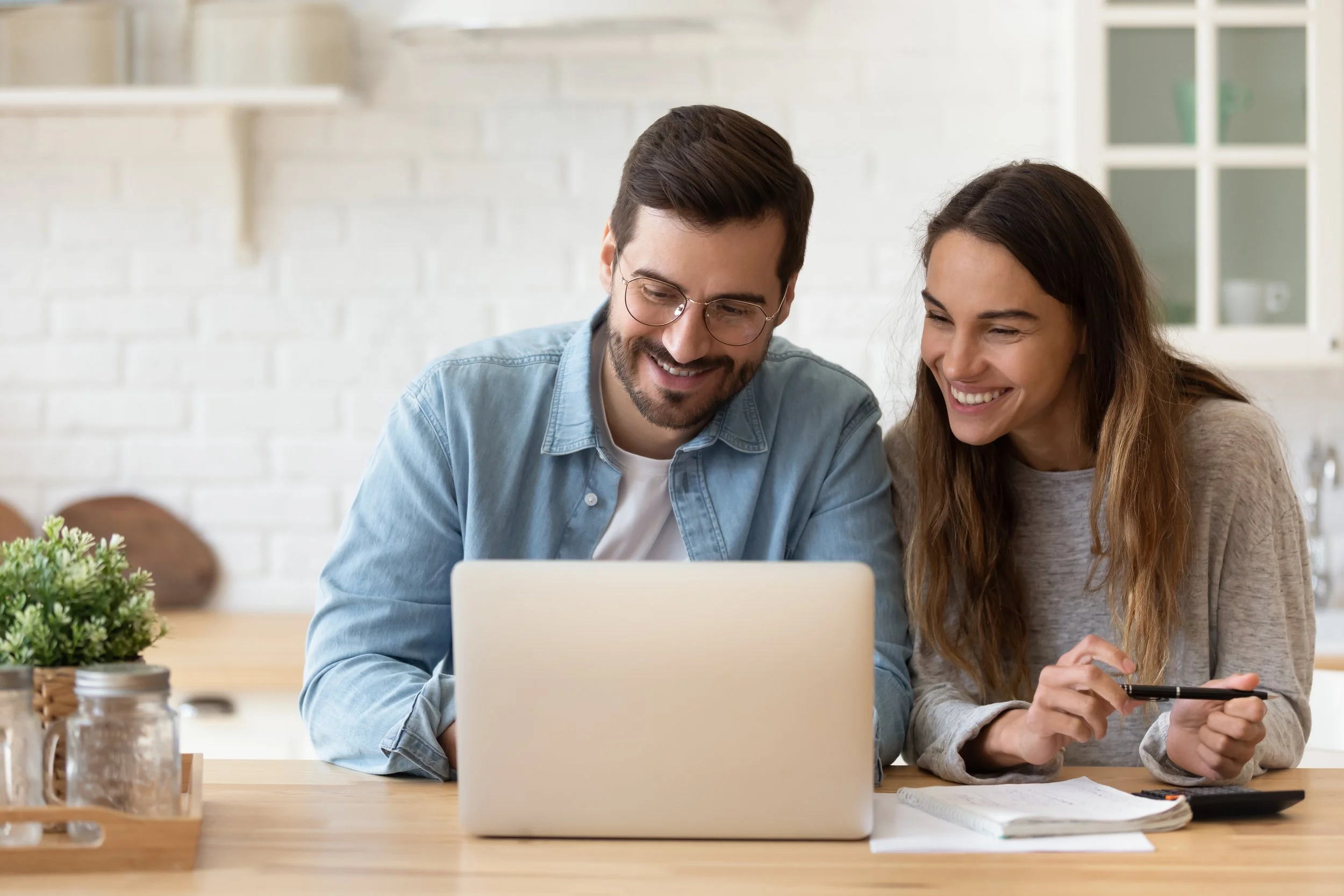 A couple both smiling looking at a laptop