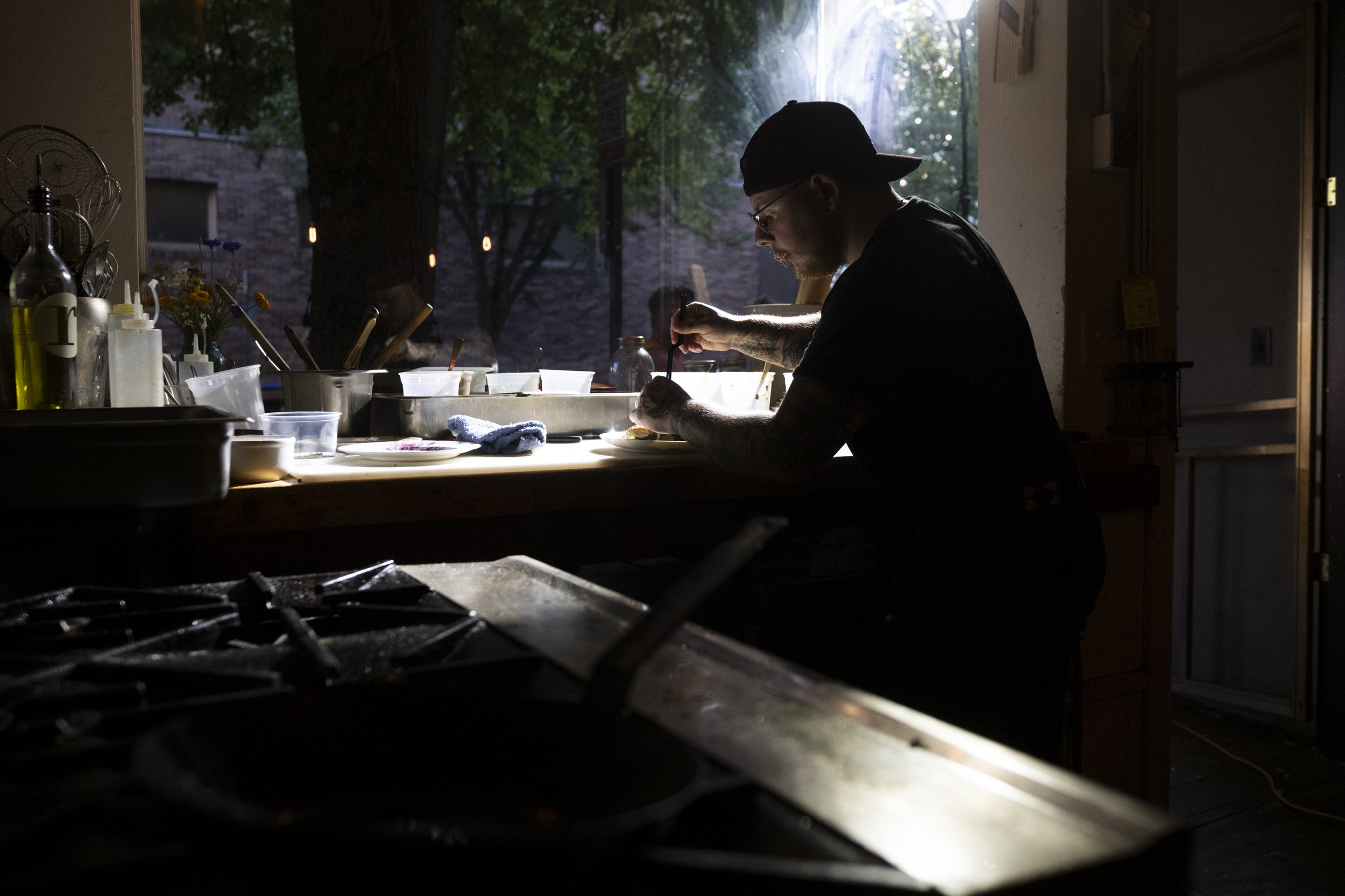 Executive Chef John Thomas prepares a dish in a darkened kitchen at Thistle Restaurant
