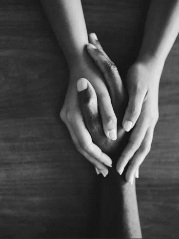 A young girl with braided hair and a starry dress is at a food counter, receiving a drink from a woman with medium-length hair. Several people are in line in a busy indoor setting with brick walls, a Welcome sign, and various food and drink items on the counter.
