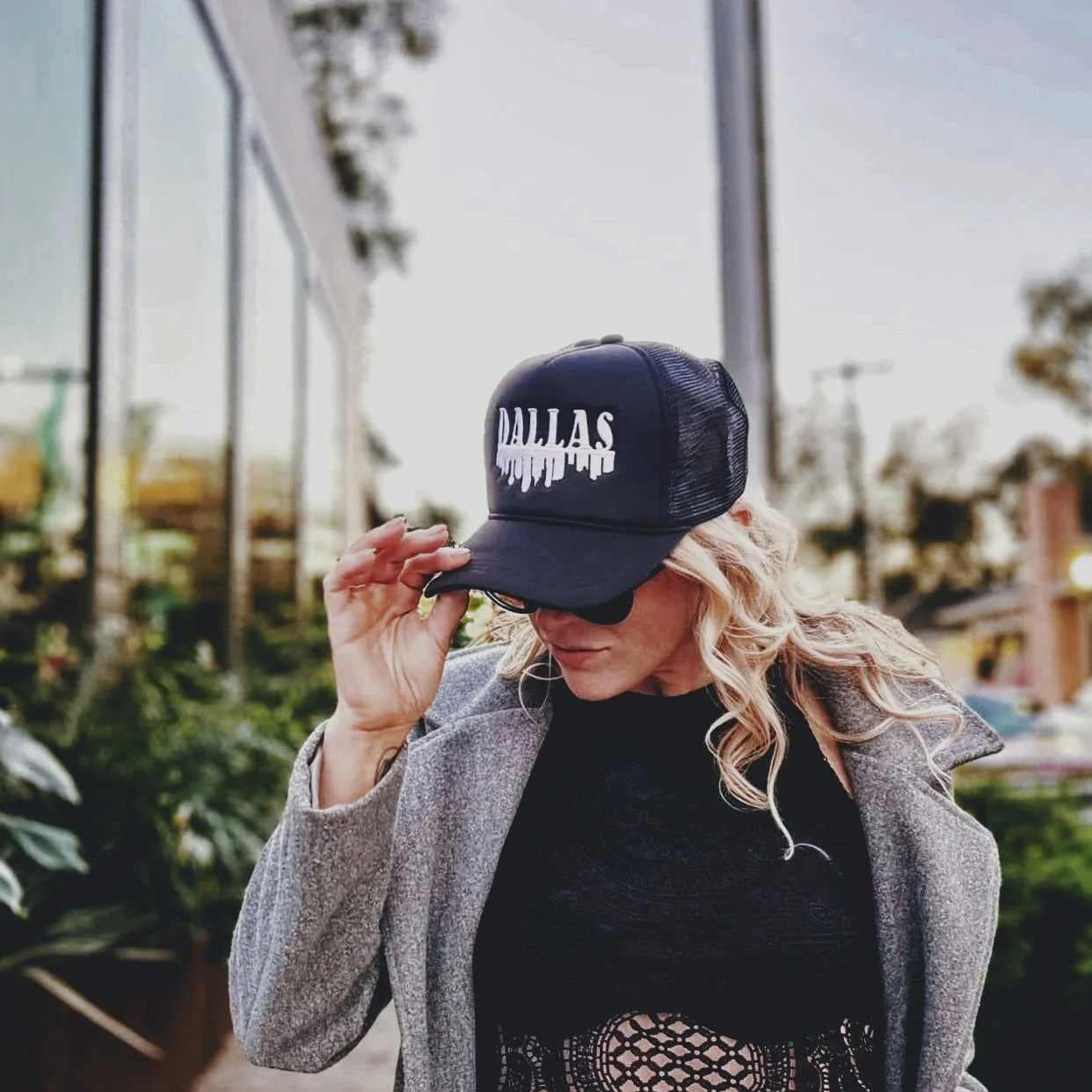 Woman wearing a black Dallas skyline trucker hat.