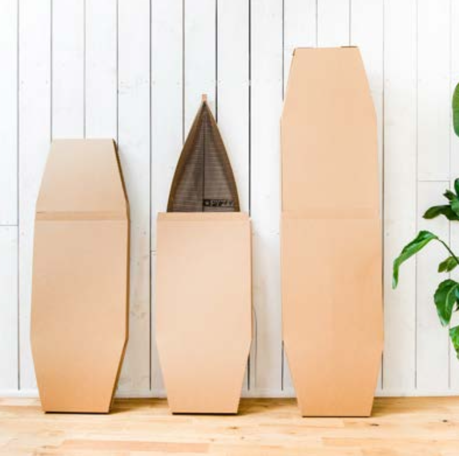 Cardboard coffin boxes against a white wooden wall