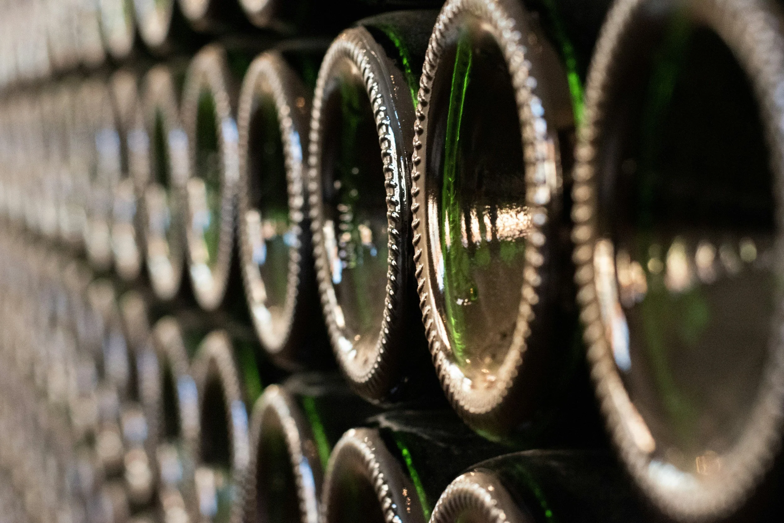Close-up of the bottom of stacked green glass bottles, focusing on their textured bases.