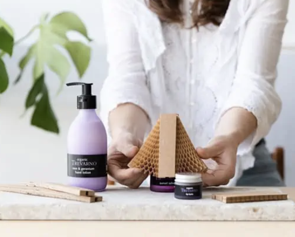 Person holding honeycomb-shaped packaging with skincare products on a table.