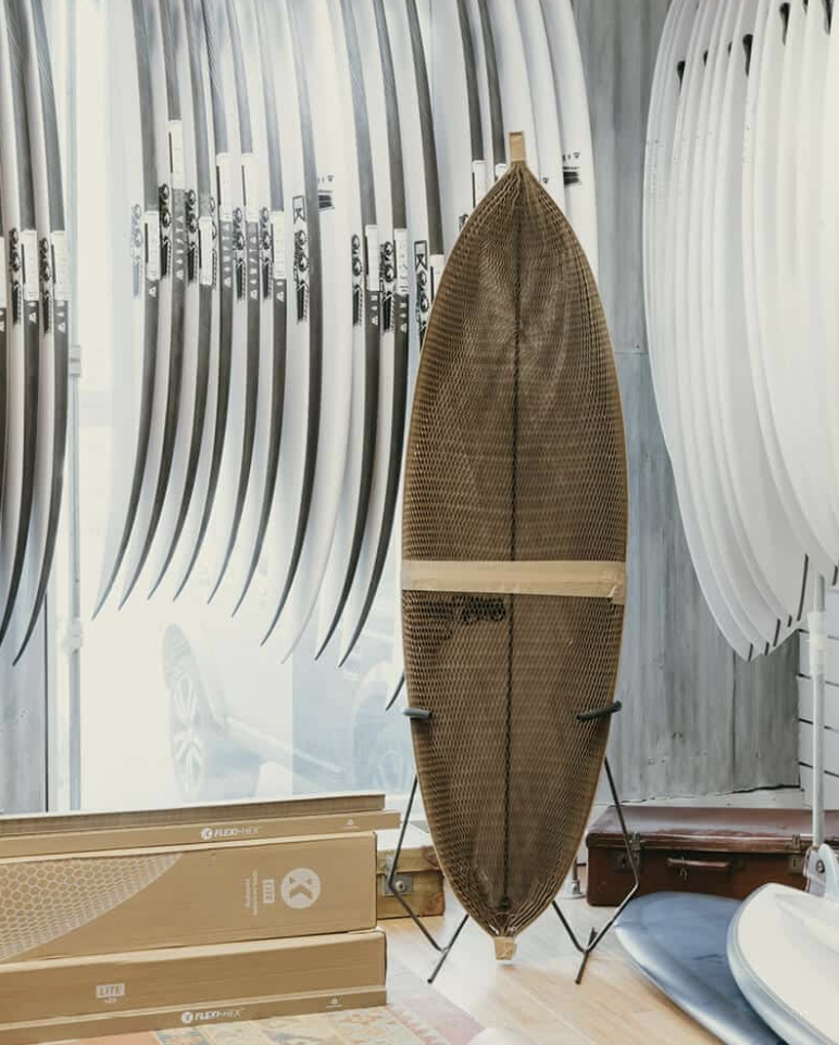 Surfboards in a shop with one in a cardboard protective cover.