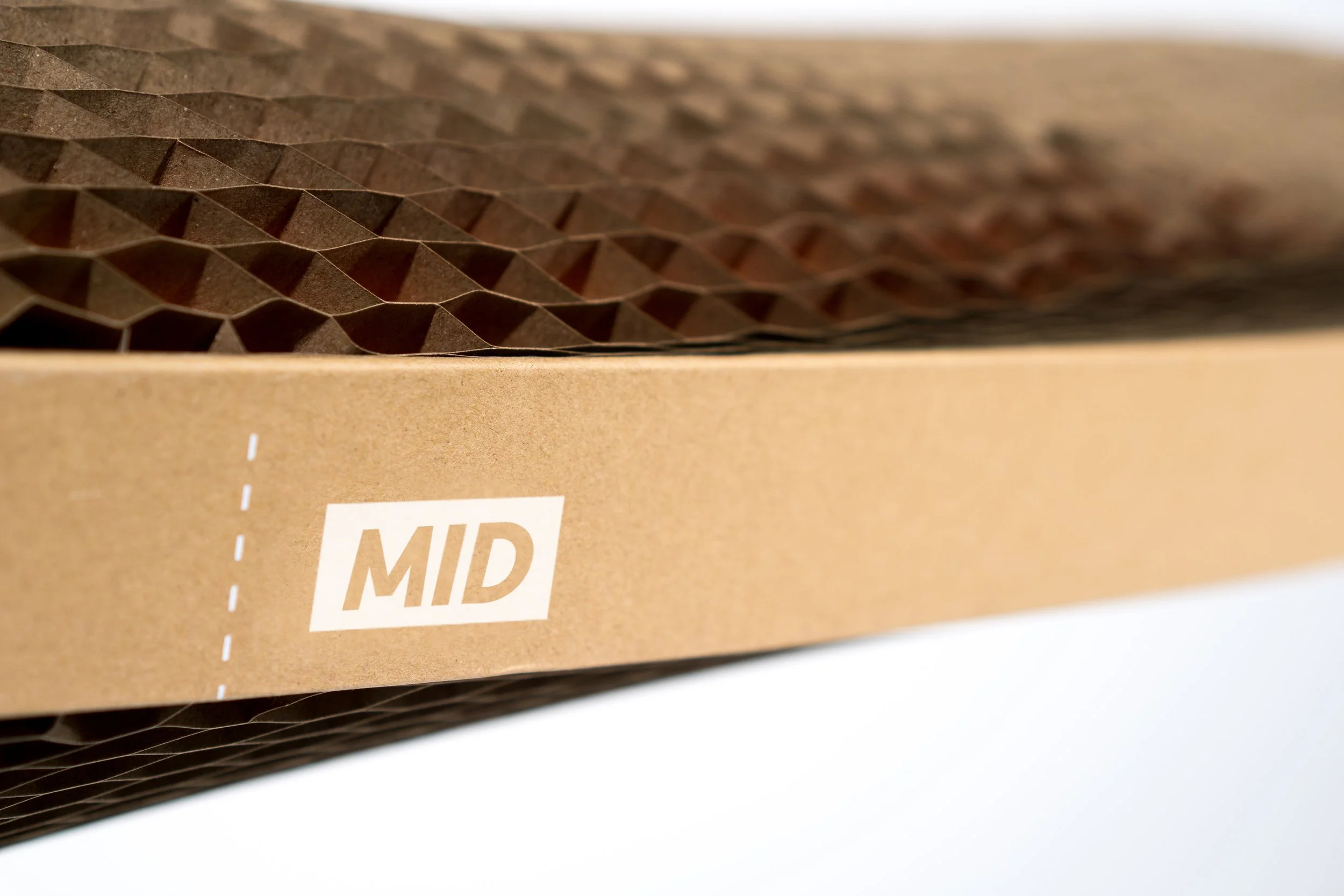 Close-up of a cardboard box with a honeycomb cardboard insert inside, labeled 'MID' on the side.