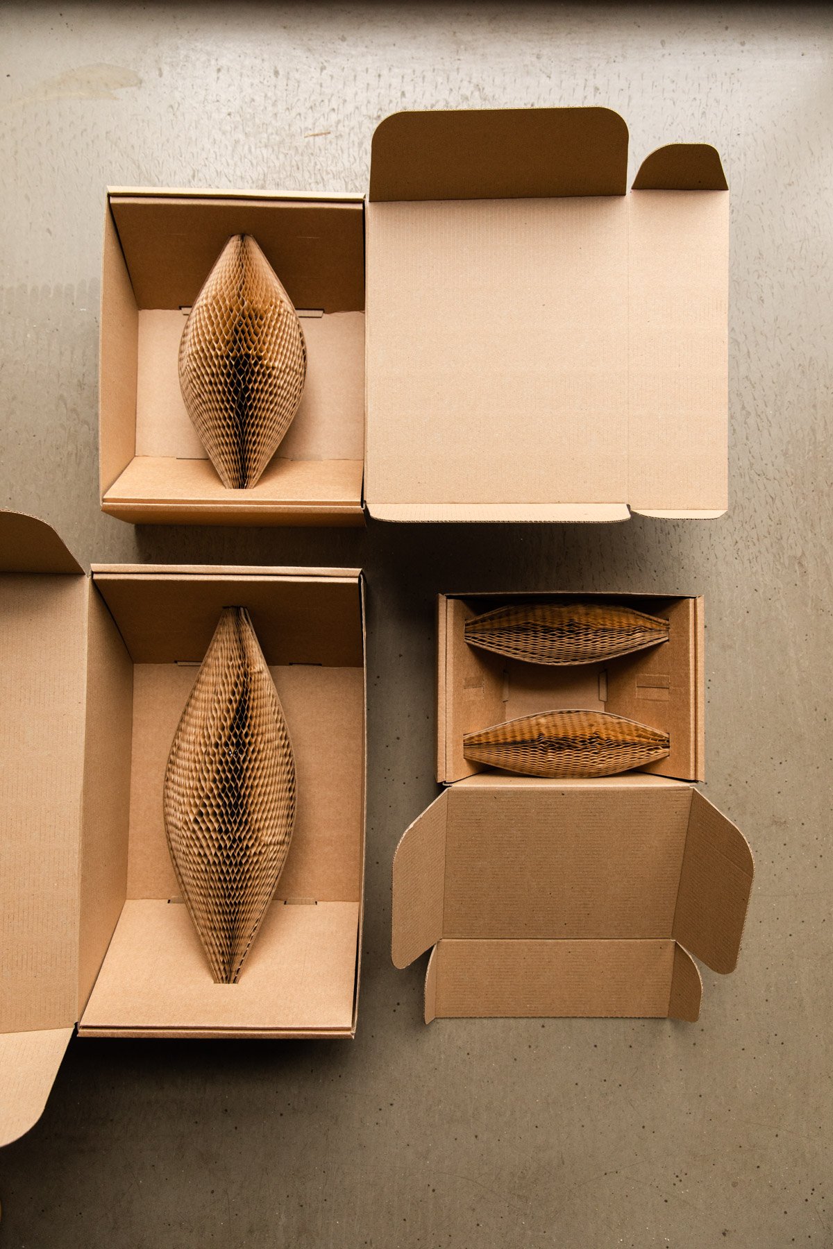 Open cardboard boxes with honeycomb paper packaging inside, placed on a gray surface.