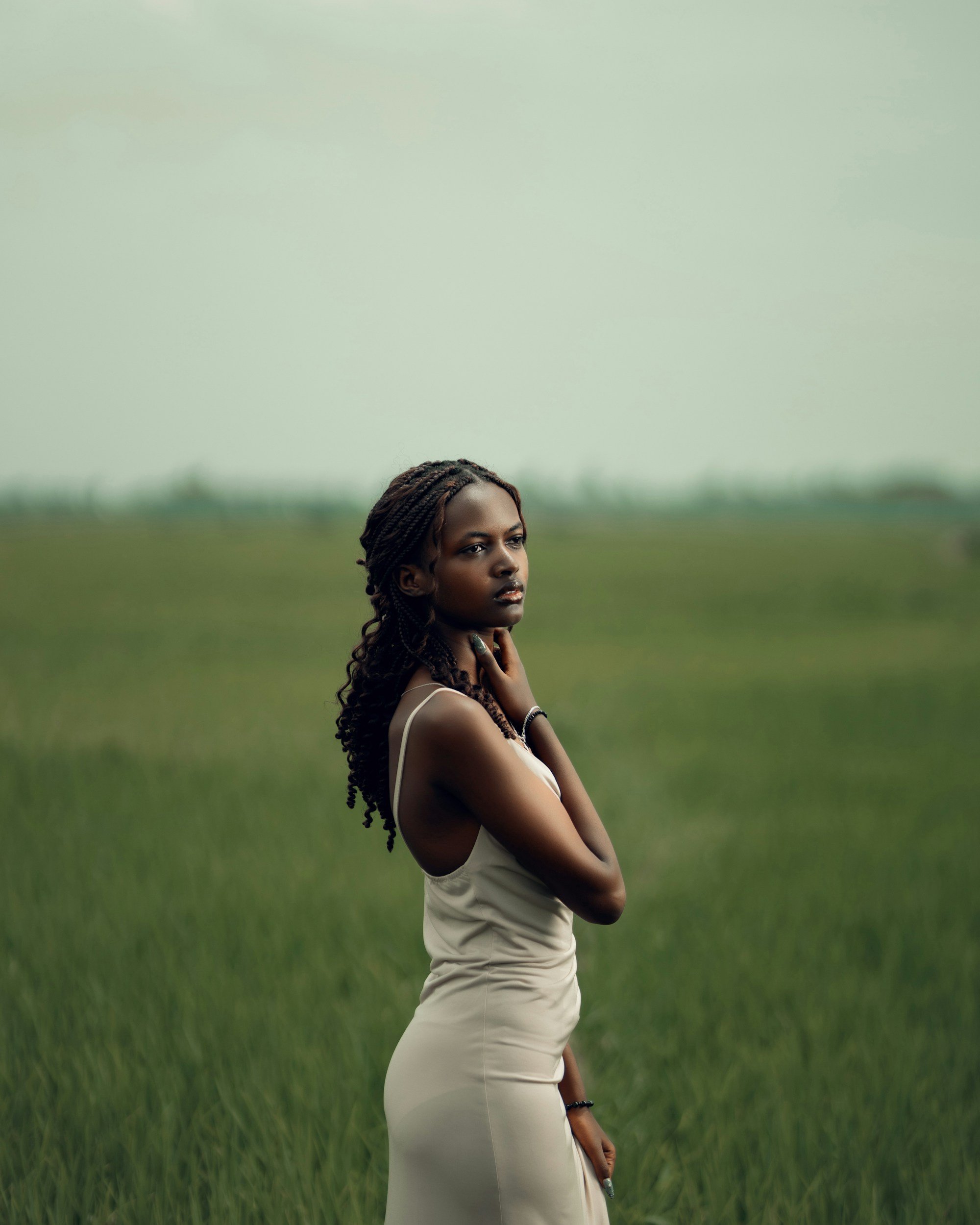 A young girl with wavy brown hair standing in a field