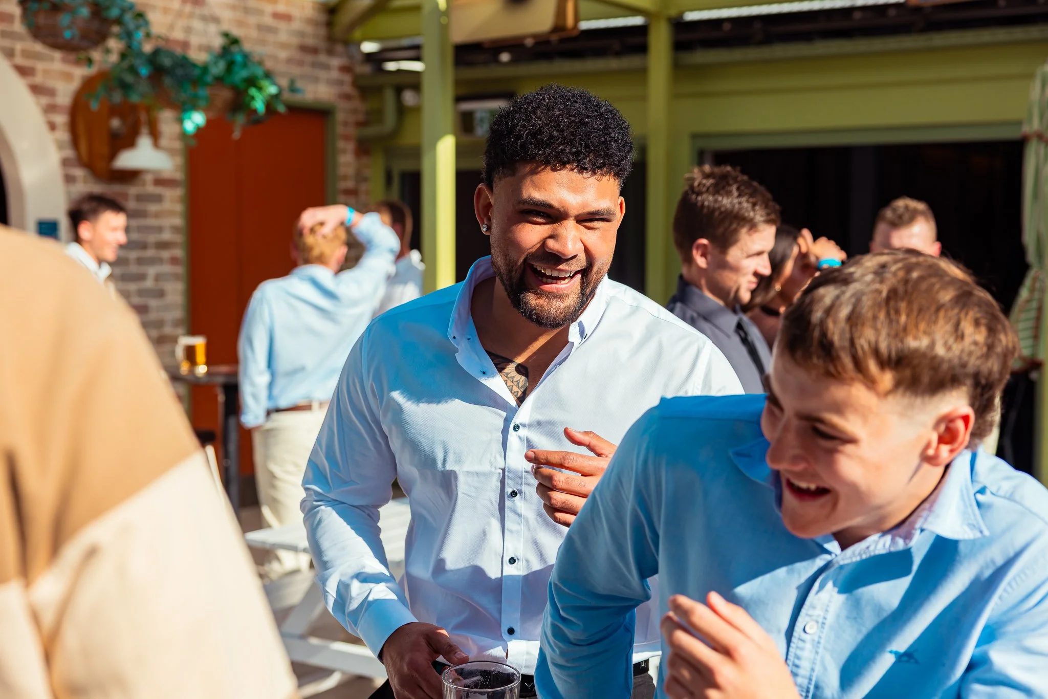 A group of people socializing outdoors at a party or gathering, with one man smiling and engaging in conversation.