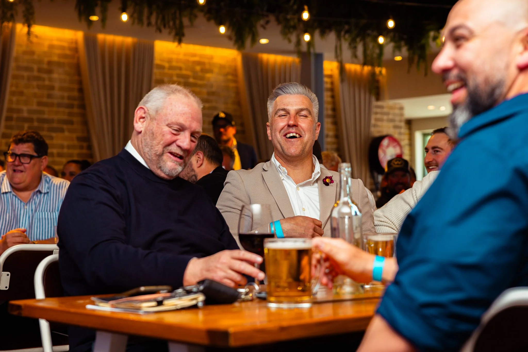 Group of men enjoying drinks and conversation at a social gathering or party in a warmly lit indoor setting.