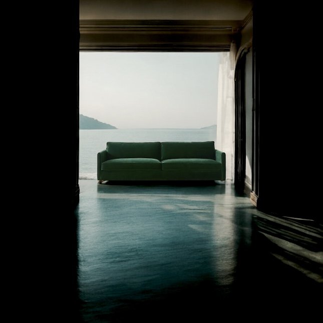 Green sofa in a room with ocean view through large windows