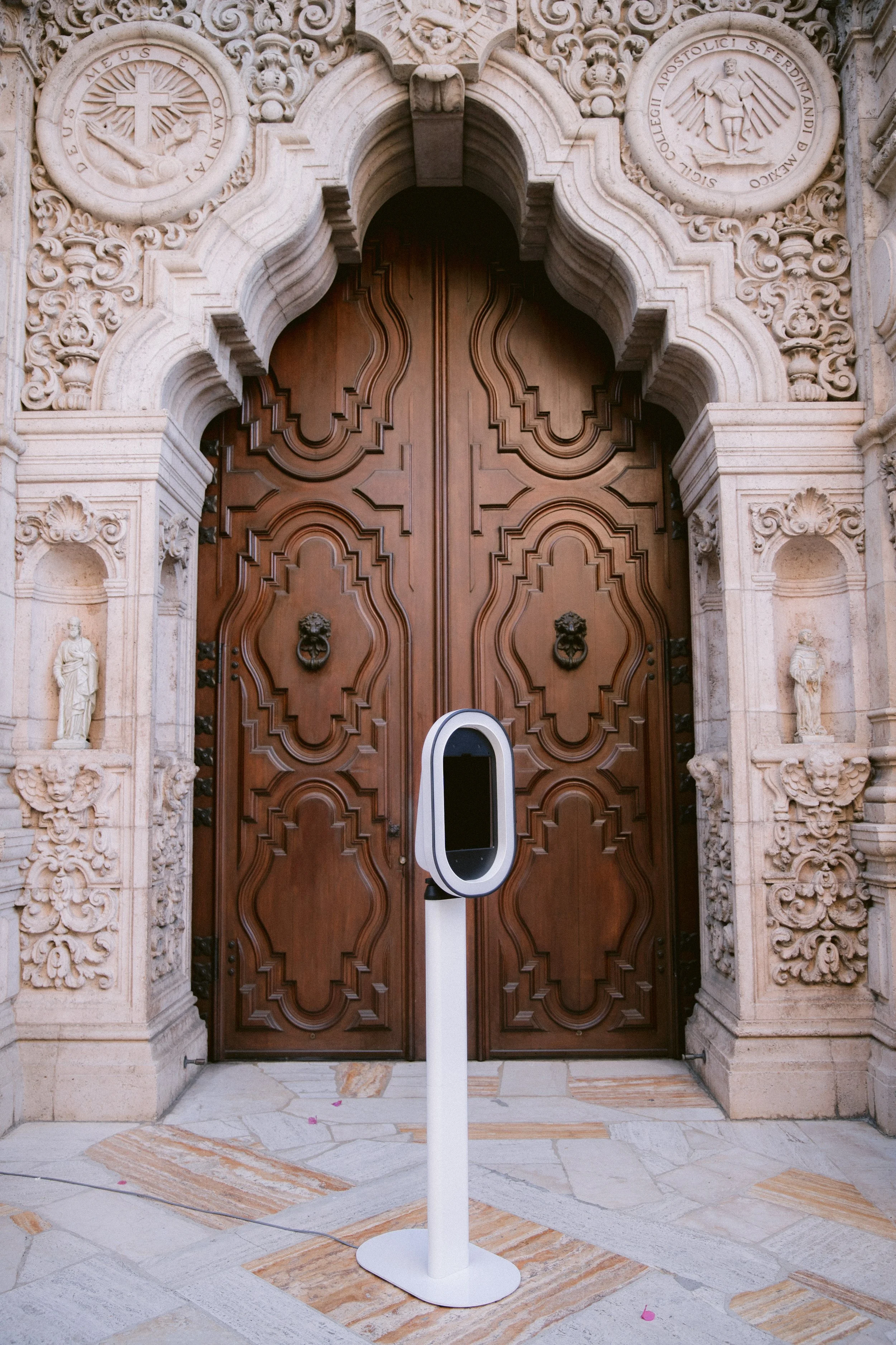 A large ornate wooden door with white photo booth standing in front of it.