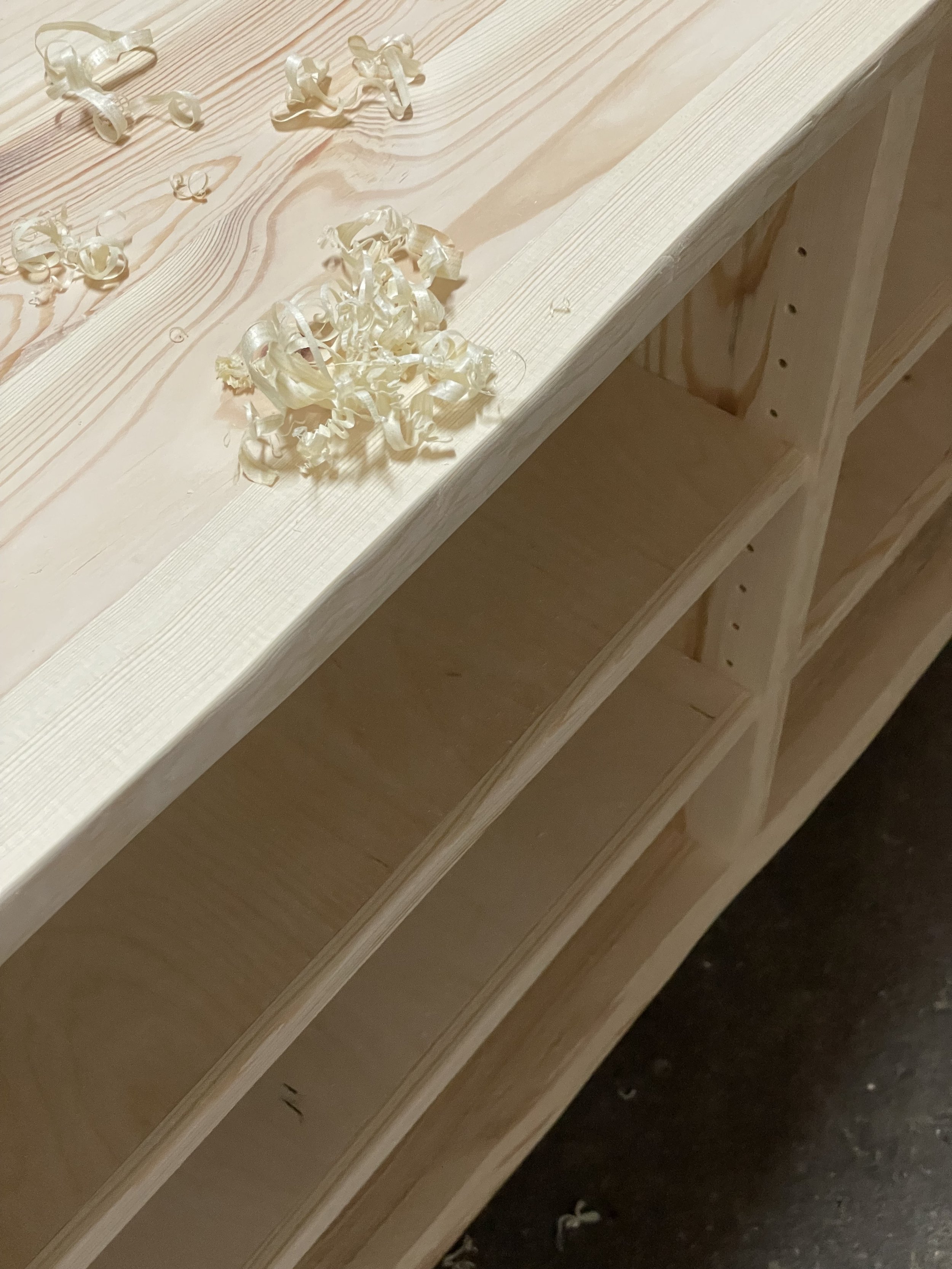 Unbehandeltes Holzregal mit Holzspänen auf der Oberfläche.