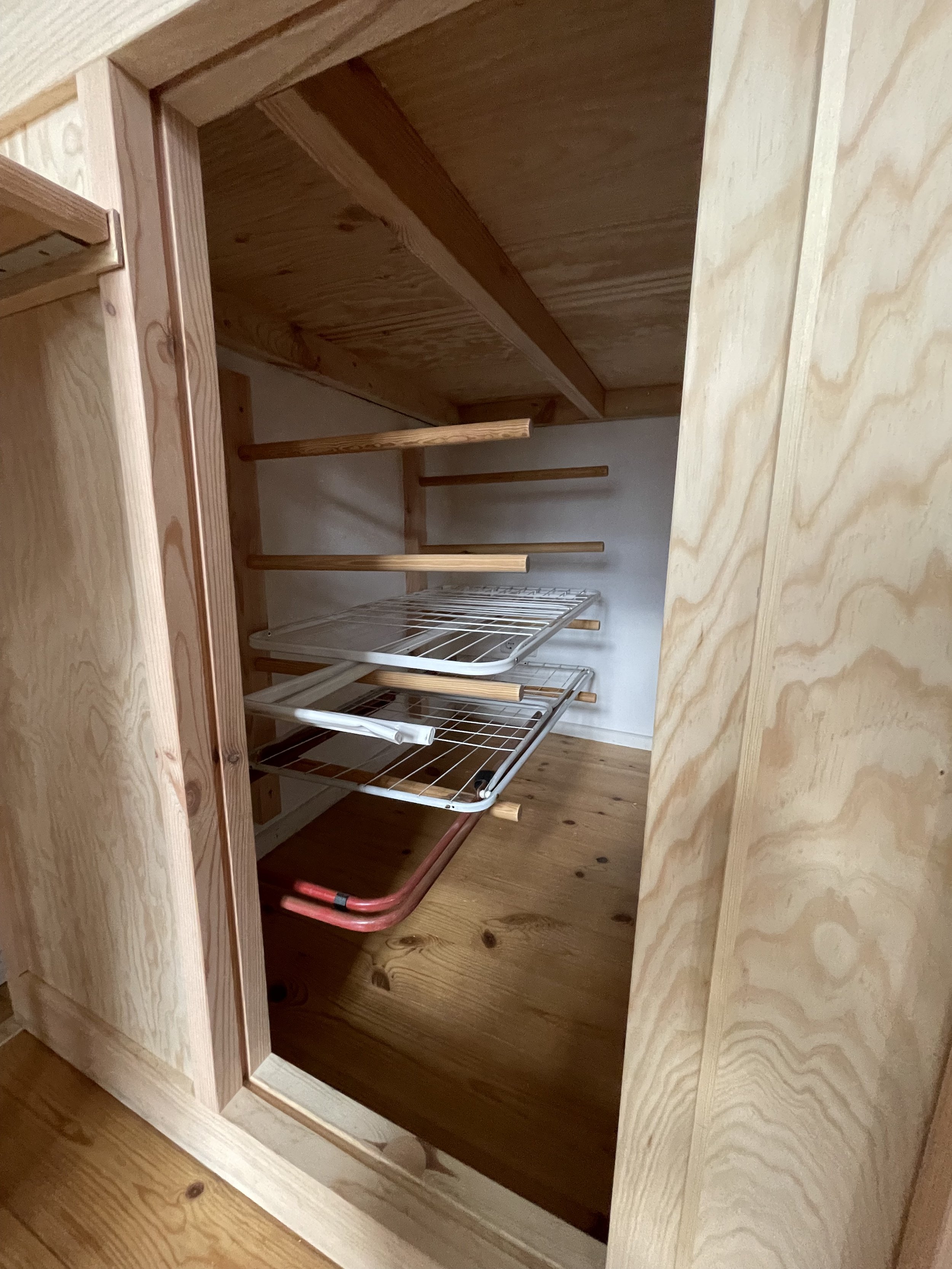 Ein leerer, Holzregal mit mehreren Wäscheständern in einem Schrank